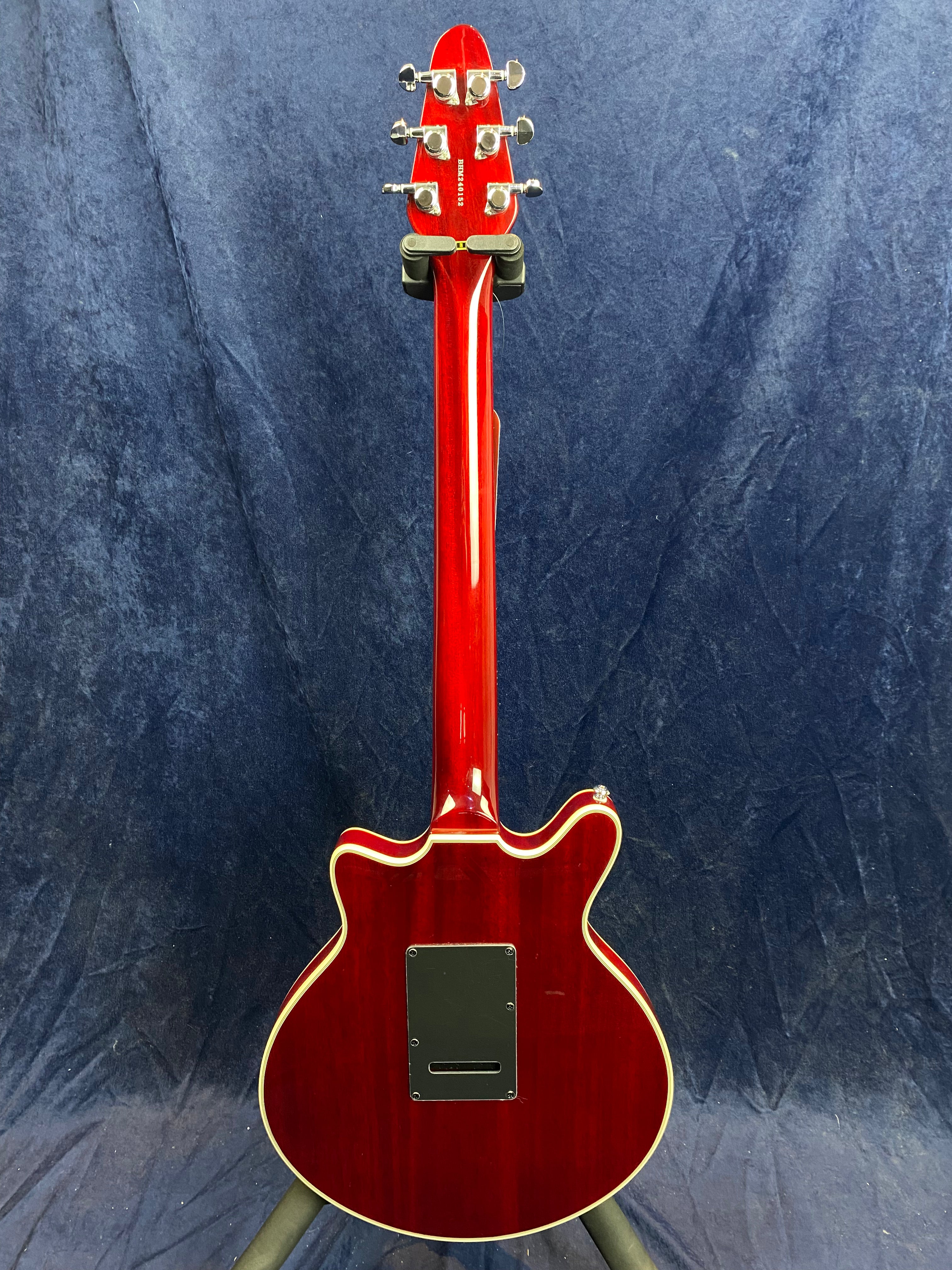 A glossy red electric guitar shown from the back, with cream binding around the body and a black plastic cover plate near the bottom.