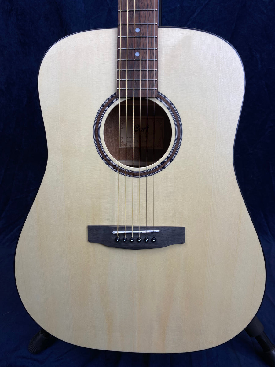 Natural wood acoustic guitar with a light-colored top, round sound hole, six strings, and a dark wood bridge and fretboard.