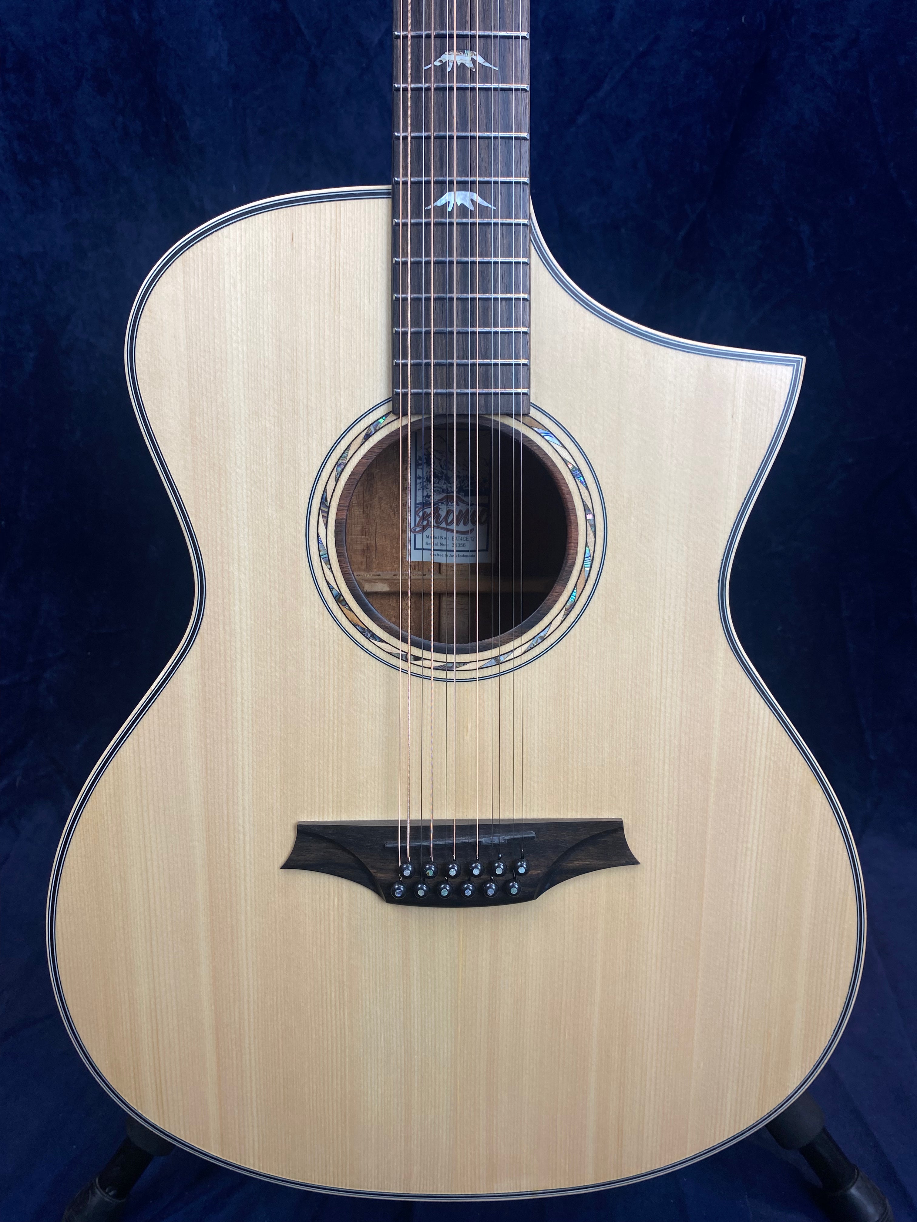 Light wood 12-string acoustic guitar with a single cutaway, rosette inlay around the sound hole, and bird-shaped inlays on the fretboard.