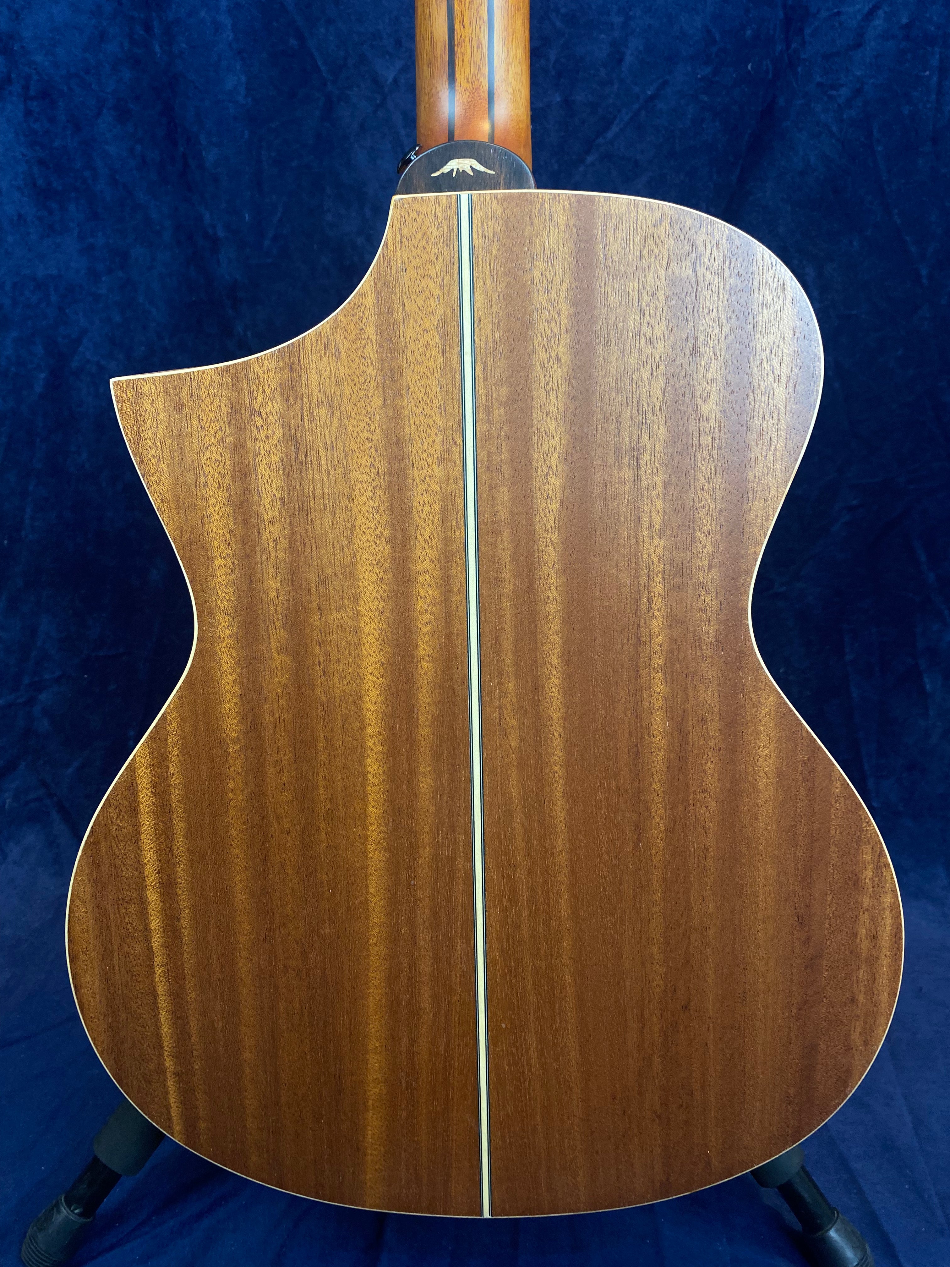 The back of an acoustic guitar made of smooth, rich brown wood with a thin, light-colored vertical stripe down the center.