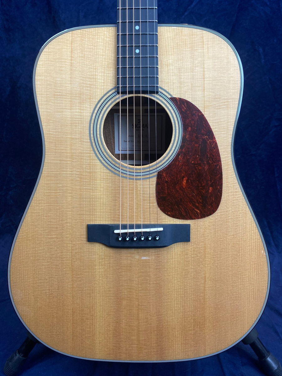 Acoustic guitar with a light wood body, black bridge, six strings, dark tortoiseshell pickguard, and concentric circle soundhole design.