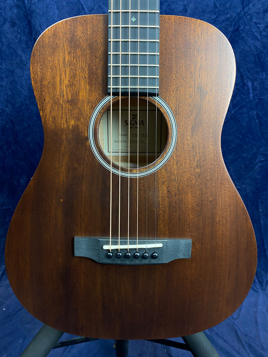 Sigma acoustic guitar with a dark wood finish, six steel strings, black bridge, and a circular sound hole.