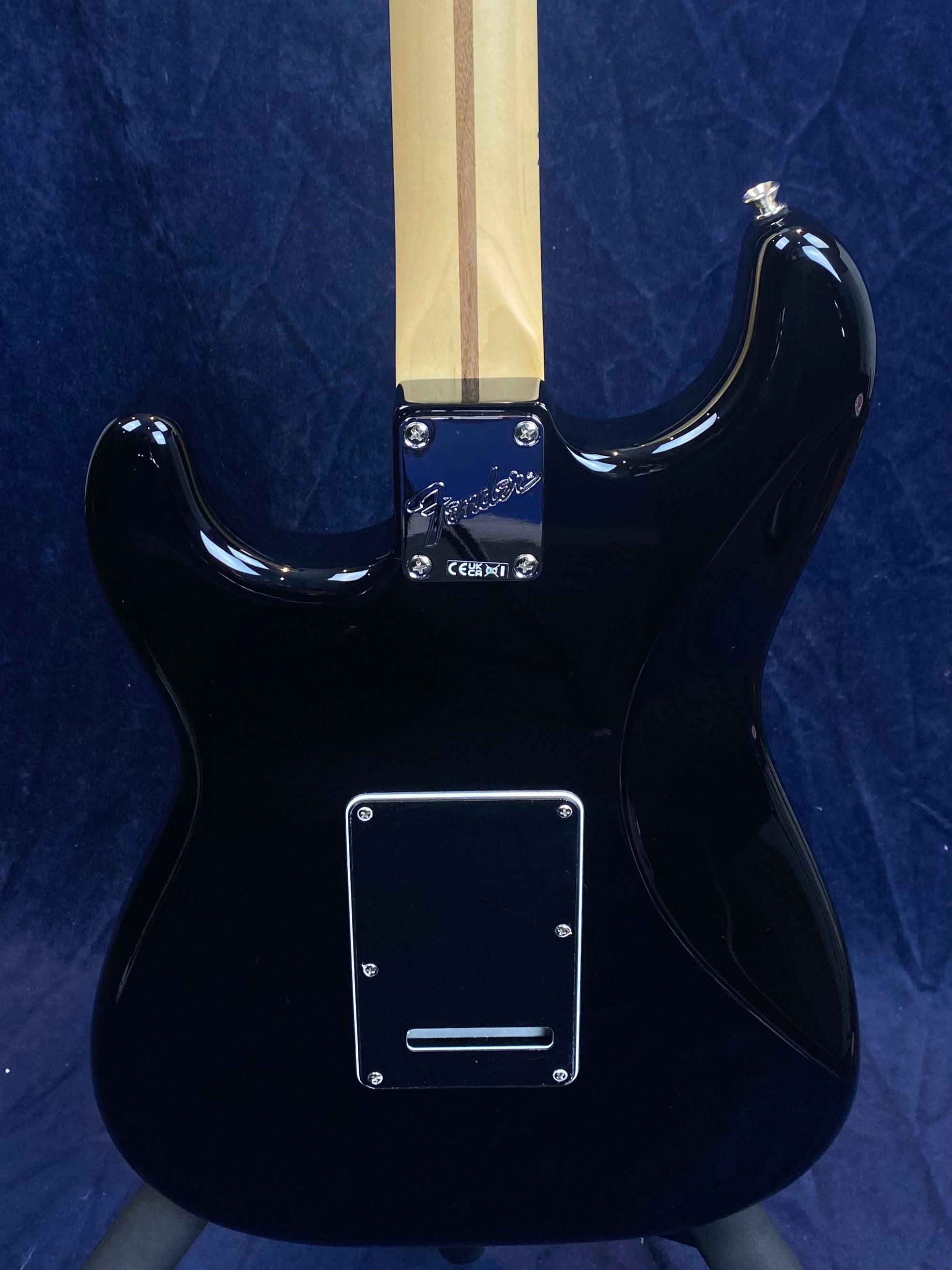 Black electric guitar rear, light wood neck with central stripe, chrome Fender neck plate, rectangular back cover plate secured with screws.