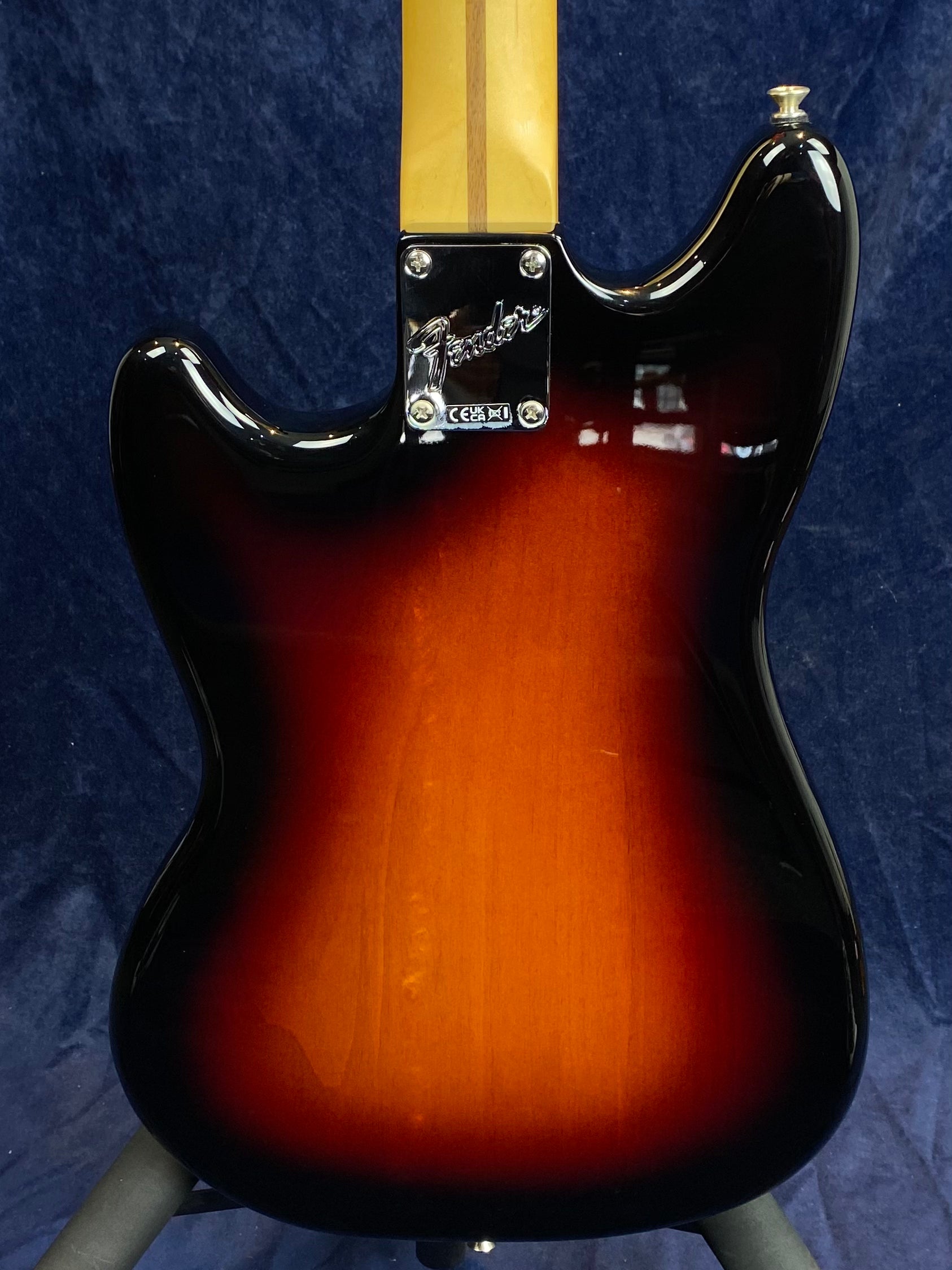 Back of a Fender electric guitar with a sunburst finish, maple neck, and chrome neck plate engraved with the Fender logo.