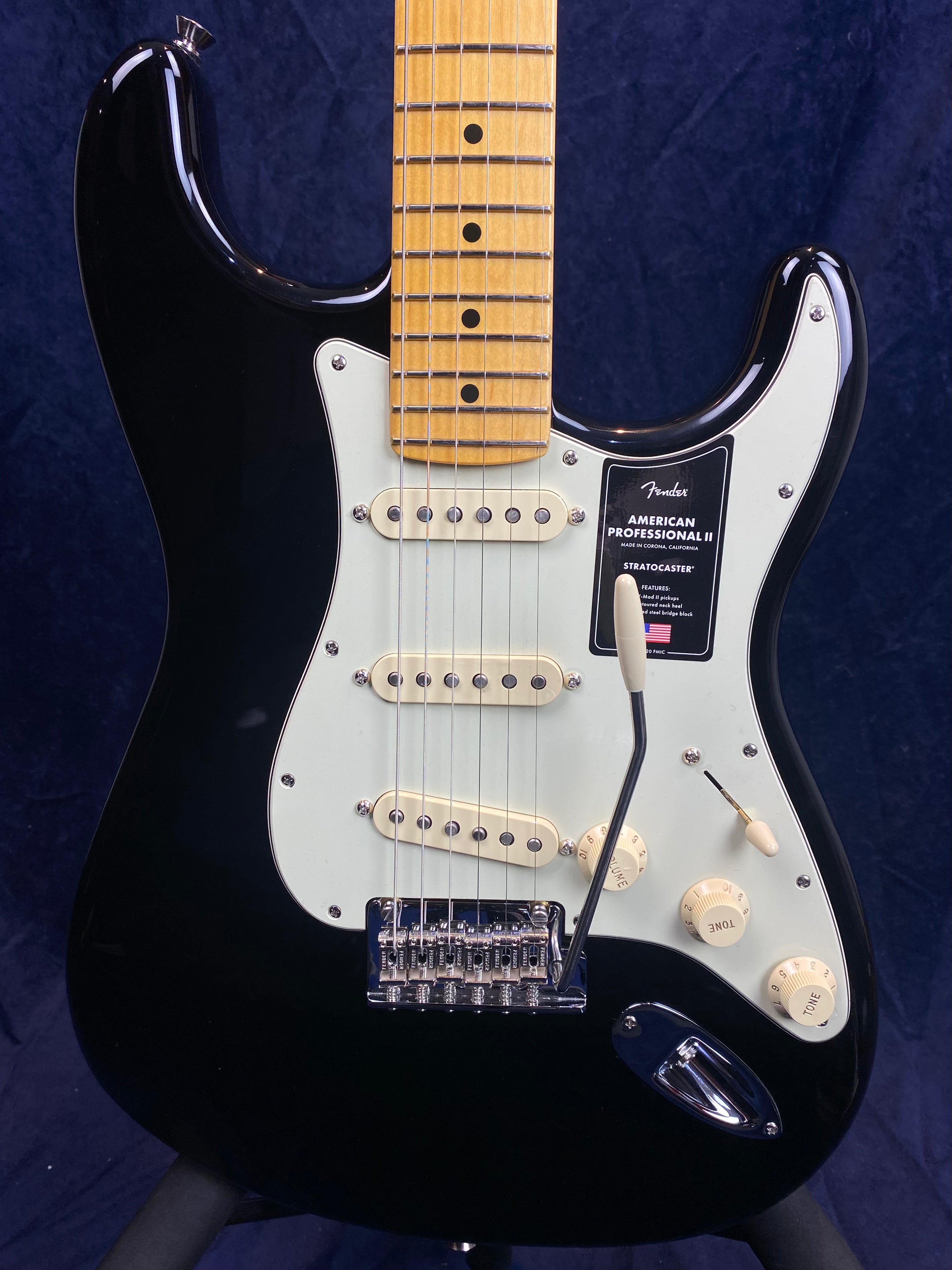 Black Fender Stratocaster electric guitar with white pickguard, three single-coil pickups, maple neck, and cream control knobs.