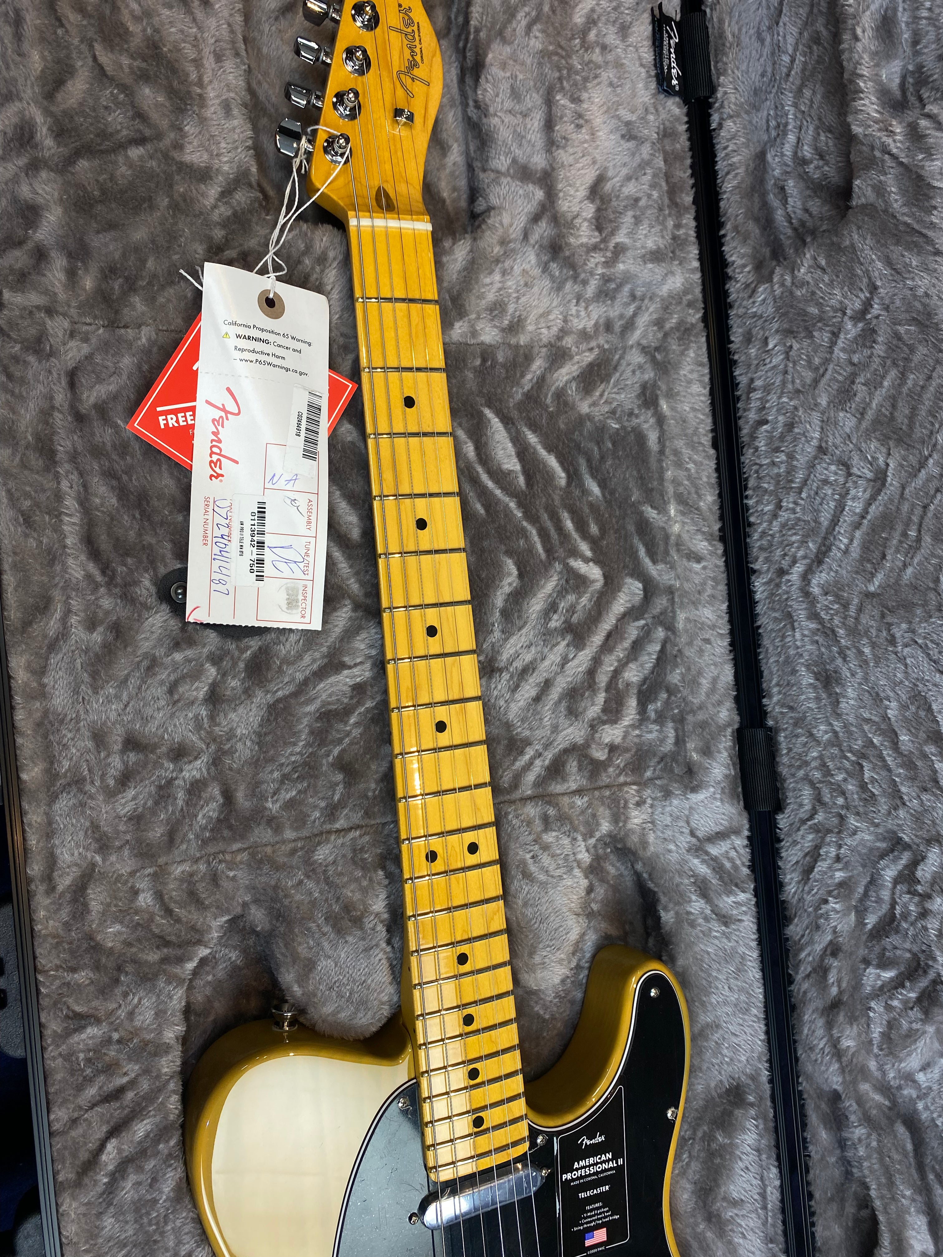Fender American Professional II Telecaster electric guitar with a light yellow body, black pickguard, maple neck, and factory tags attached to the headstock.