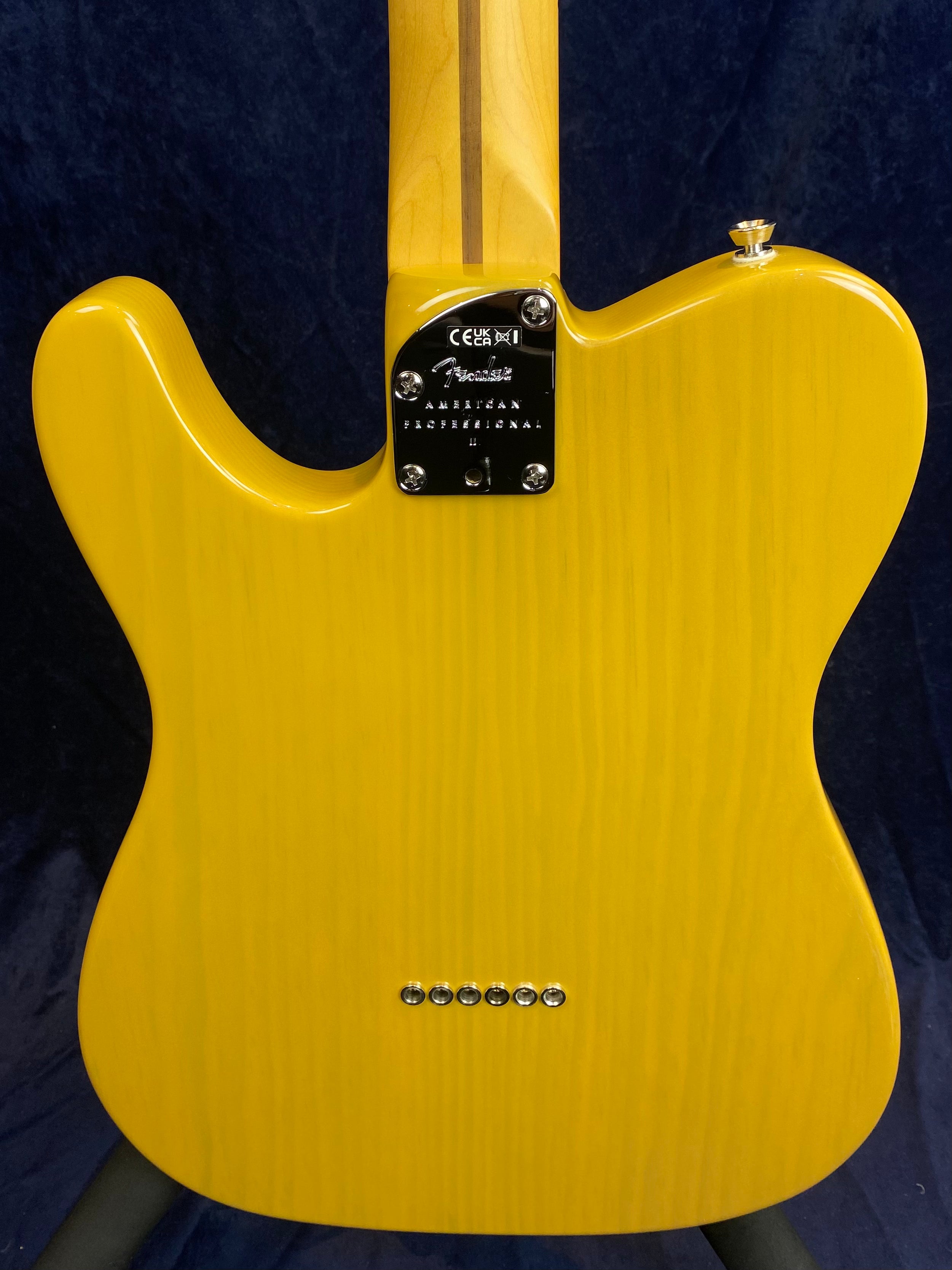 Yellow Fender electric guitar, rear view, showing the neck plate labeled "American Professional II" and six string ferrules lined up near the bottom.