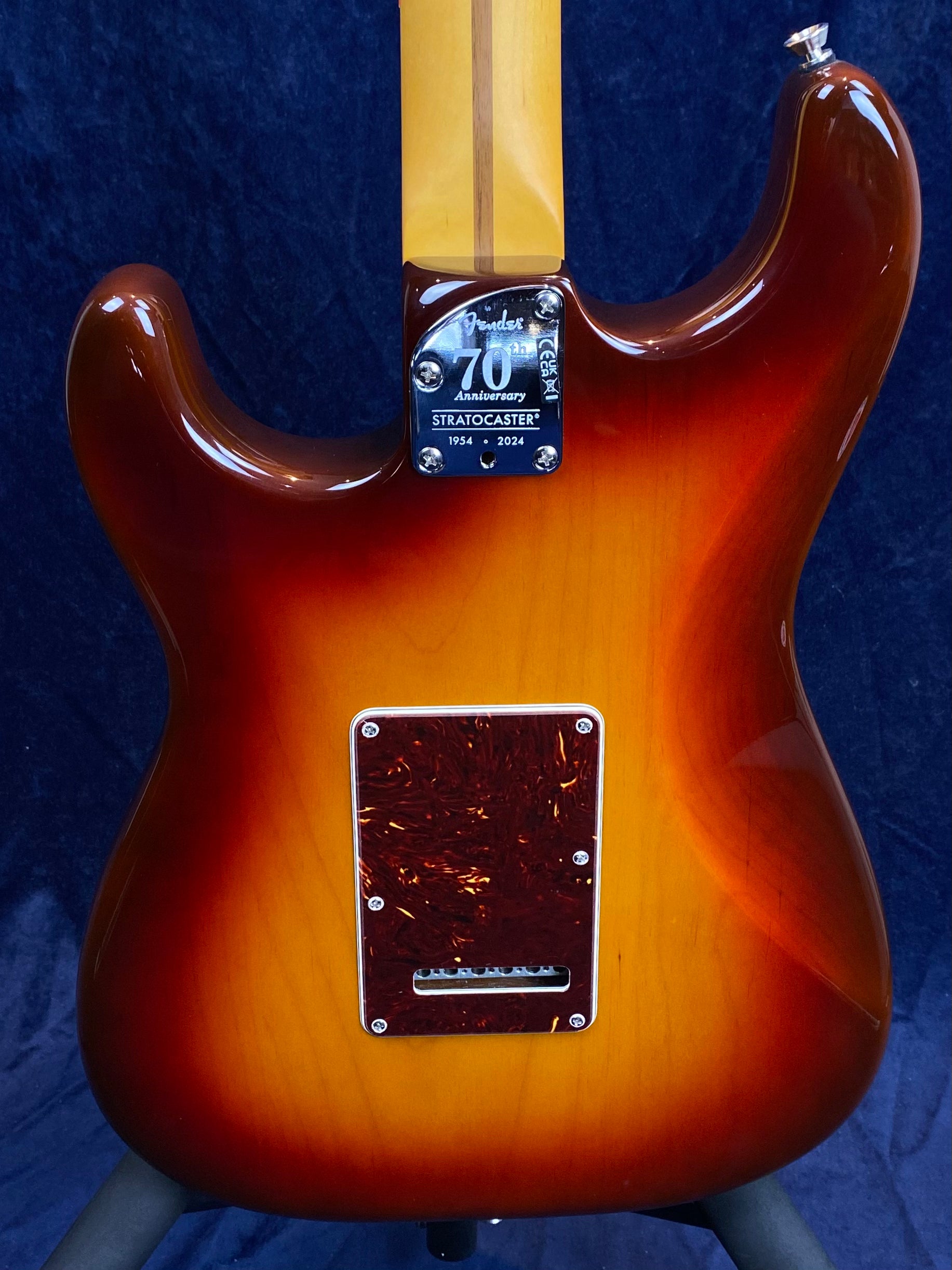Sunburst Fender Stratocaster electric guitar, 70th Anniversary neck plate reads “1954-2024,” shown from the back with brown tremolo cover.