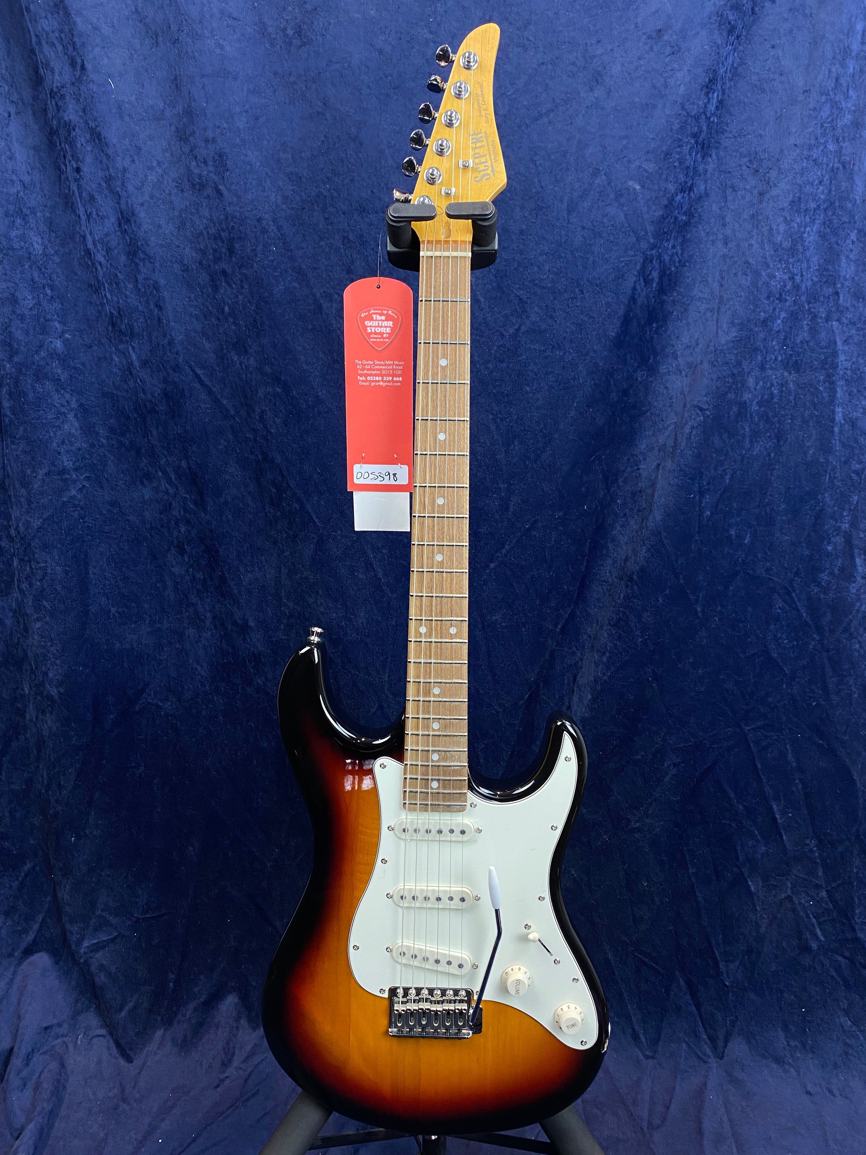 Sunburst-style electric guitar with a white pickguard, three single-coil pickups, and a maple neck, displayed upright against a dark blue background.