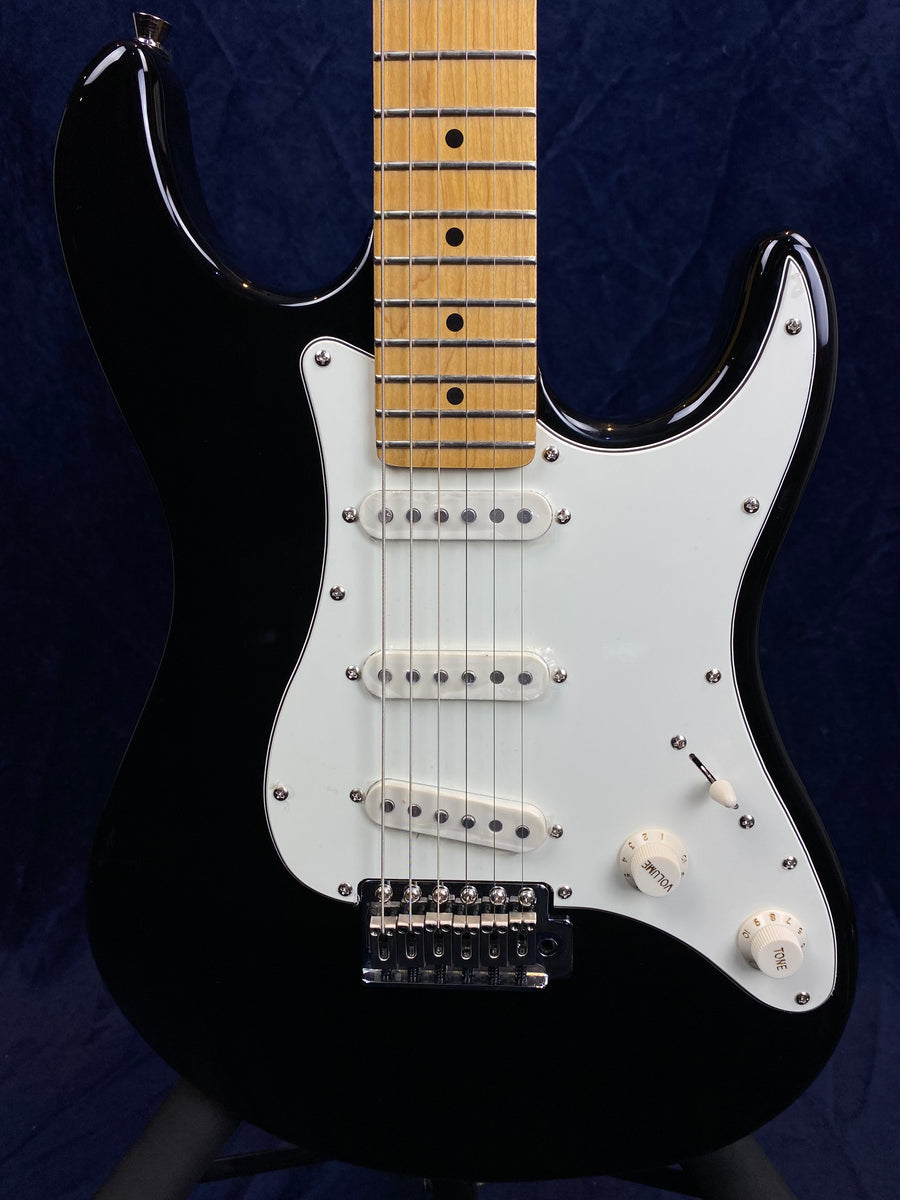 Black electric guitar with a white pickguard, three single-coil pickups, two control knobs, a switch, and a maple fretboard.