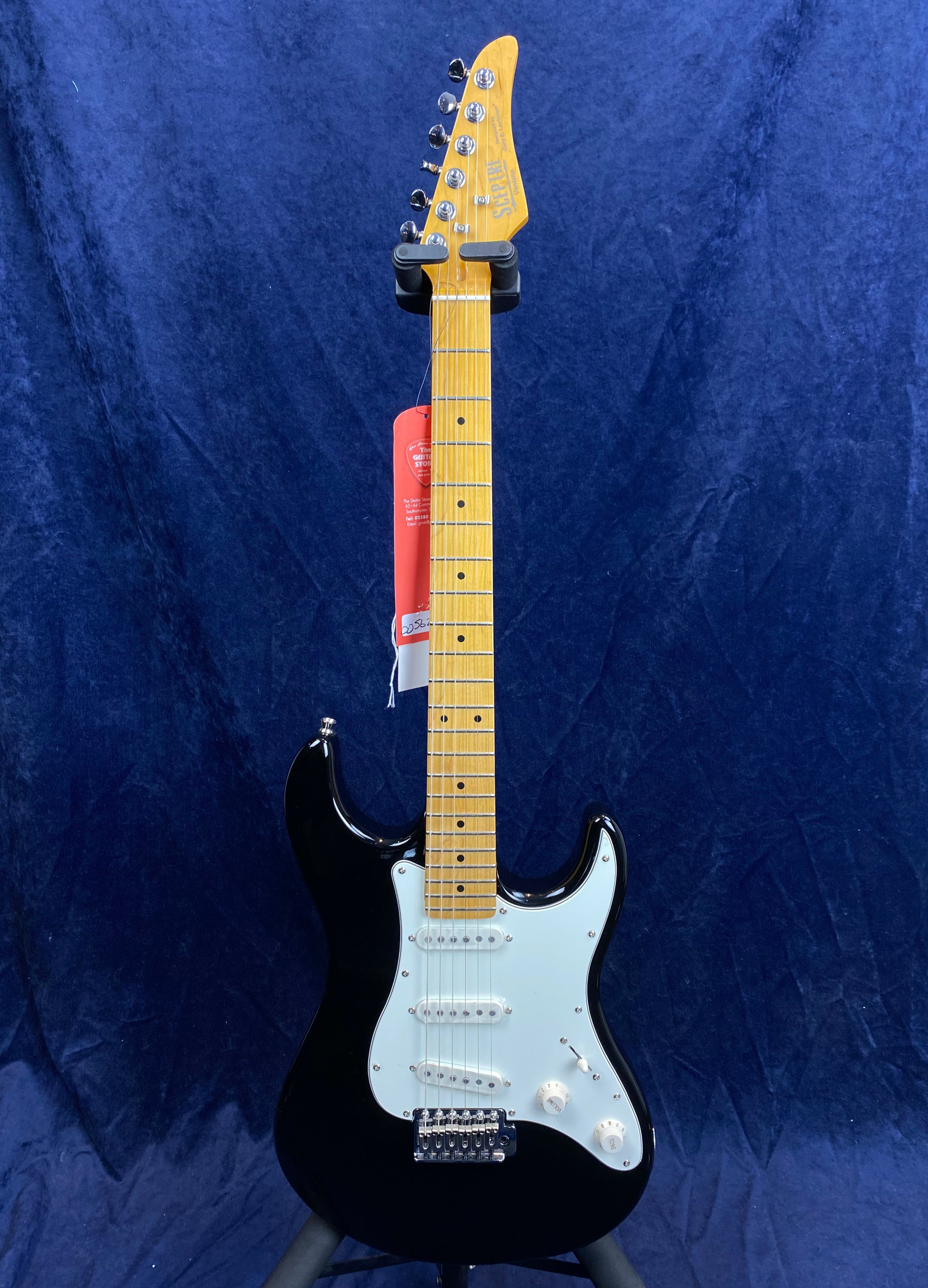 Black electric guitar with a light maple neck and fretboard, white pickguard, three single-coil pickups, and two control knobs.