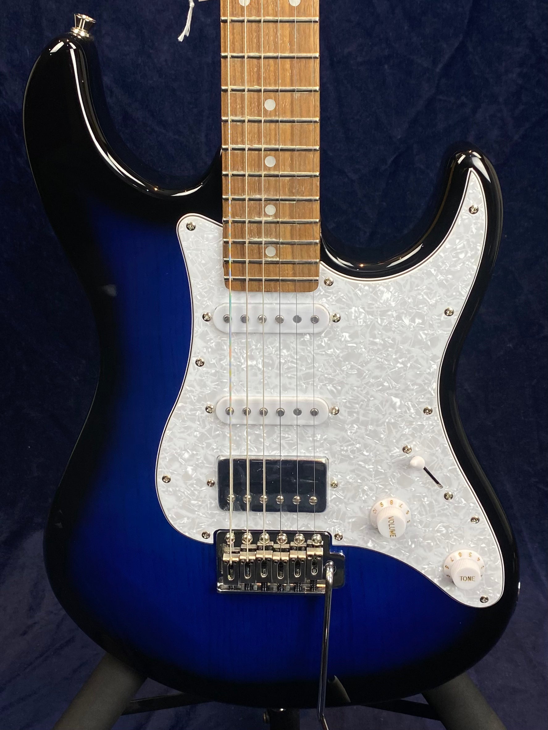 Electric guitar with a blue-to-black sunburst body, white pearloid pickguard, two white single-coil pickups, one humbucker, and chrome hardware.