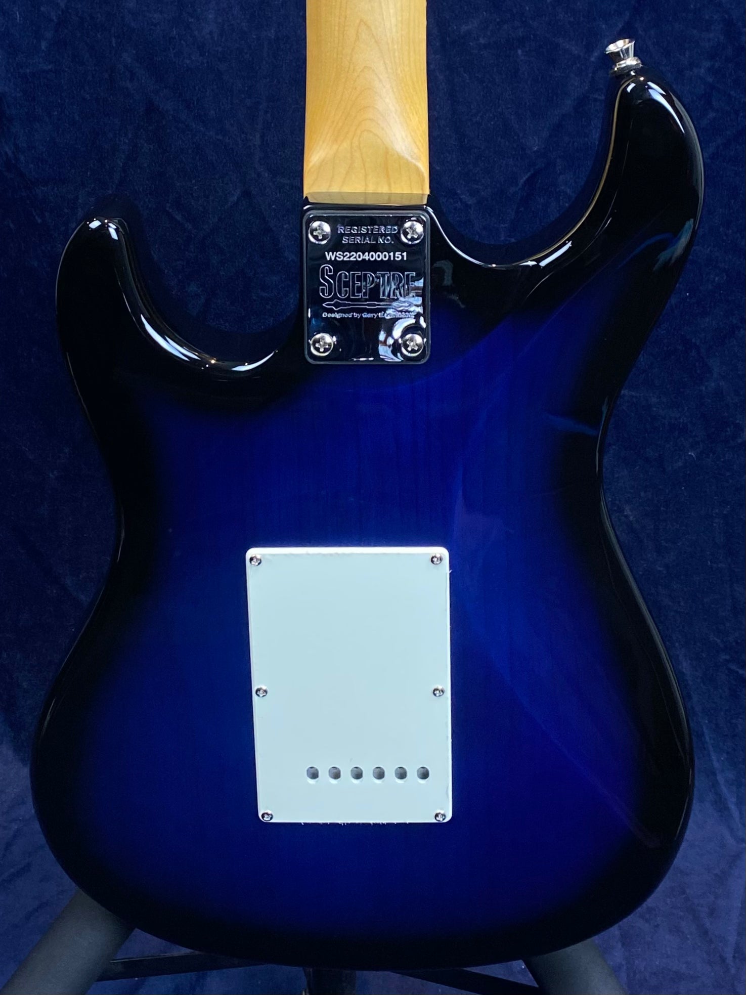 Rear view of a blue electric guitar with a white rectangular plate and "Sceptre" branding on the neck plate.
