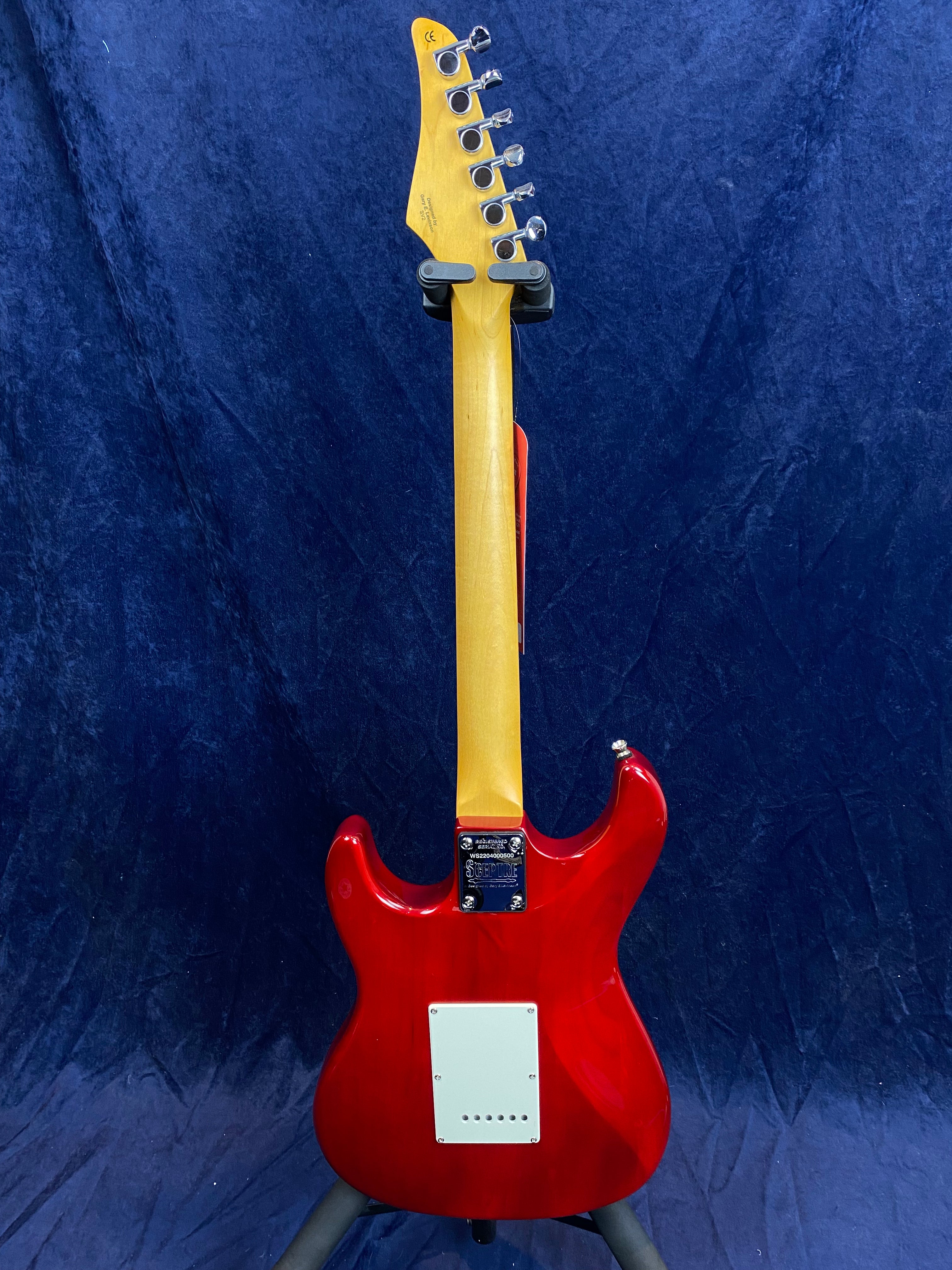 Red electric guitar seen from the back, featuring a light wood neck, chrome tuning pegs, and a white rectangular cover plate on the body.