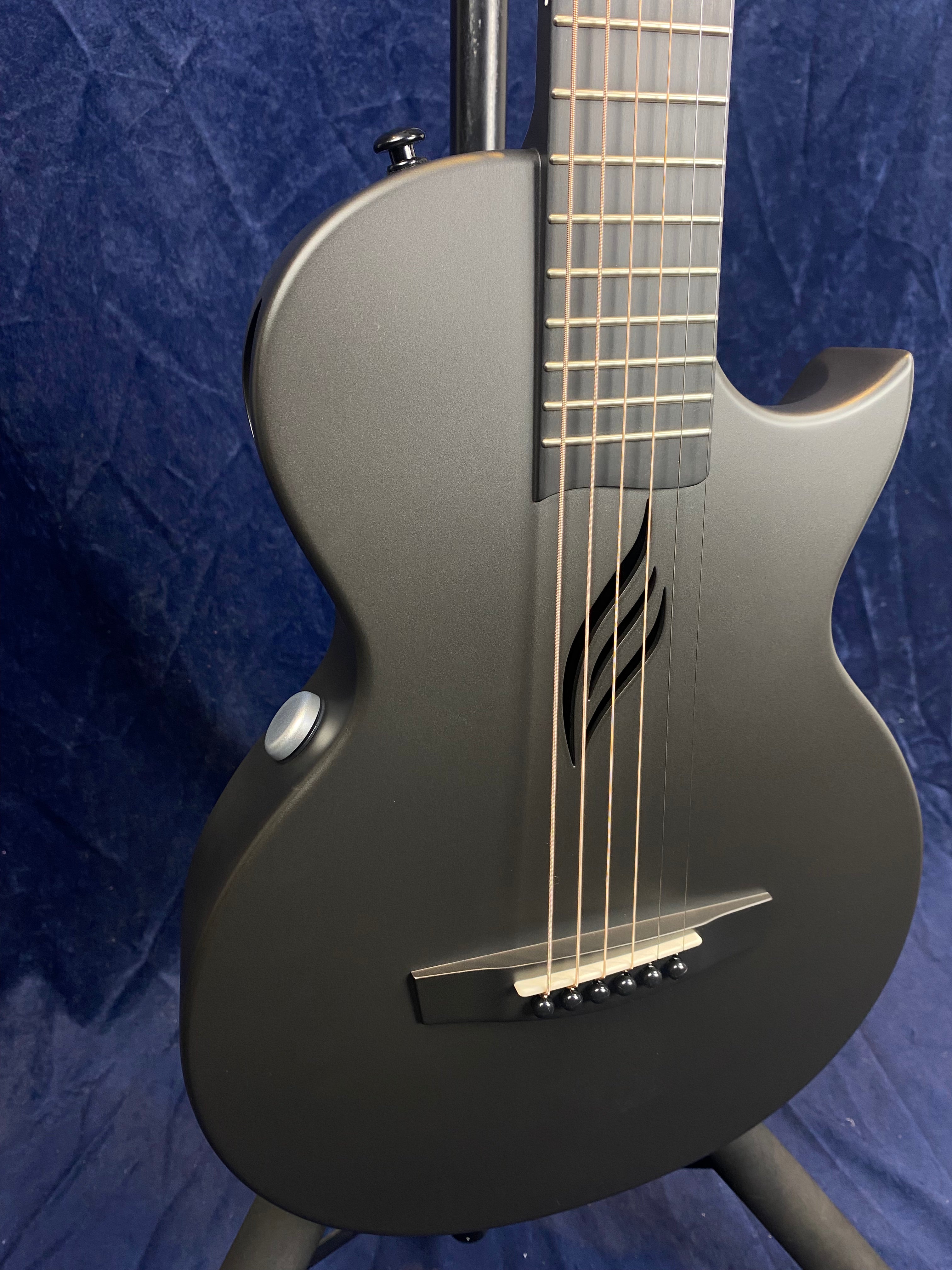 Matte black acoustic guitar with a modern, single-cutaway body and a unique leaf-shaped sound hole.