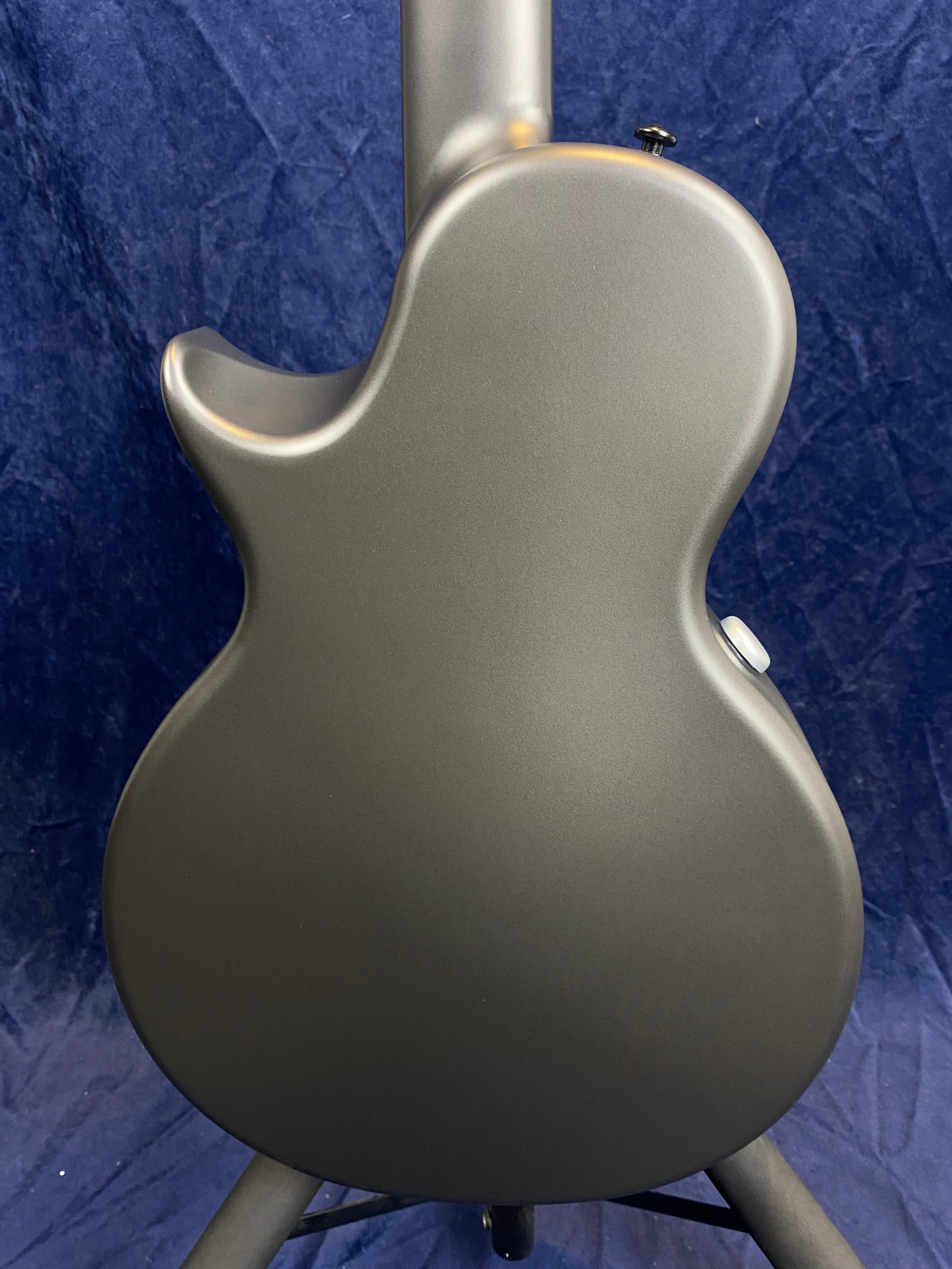 Matte gray acoustic guitar shown from the back, with a single cutaway body shape and no visible wood grain or decorative elements.