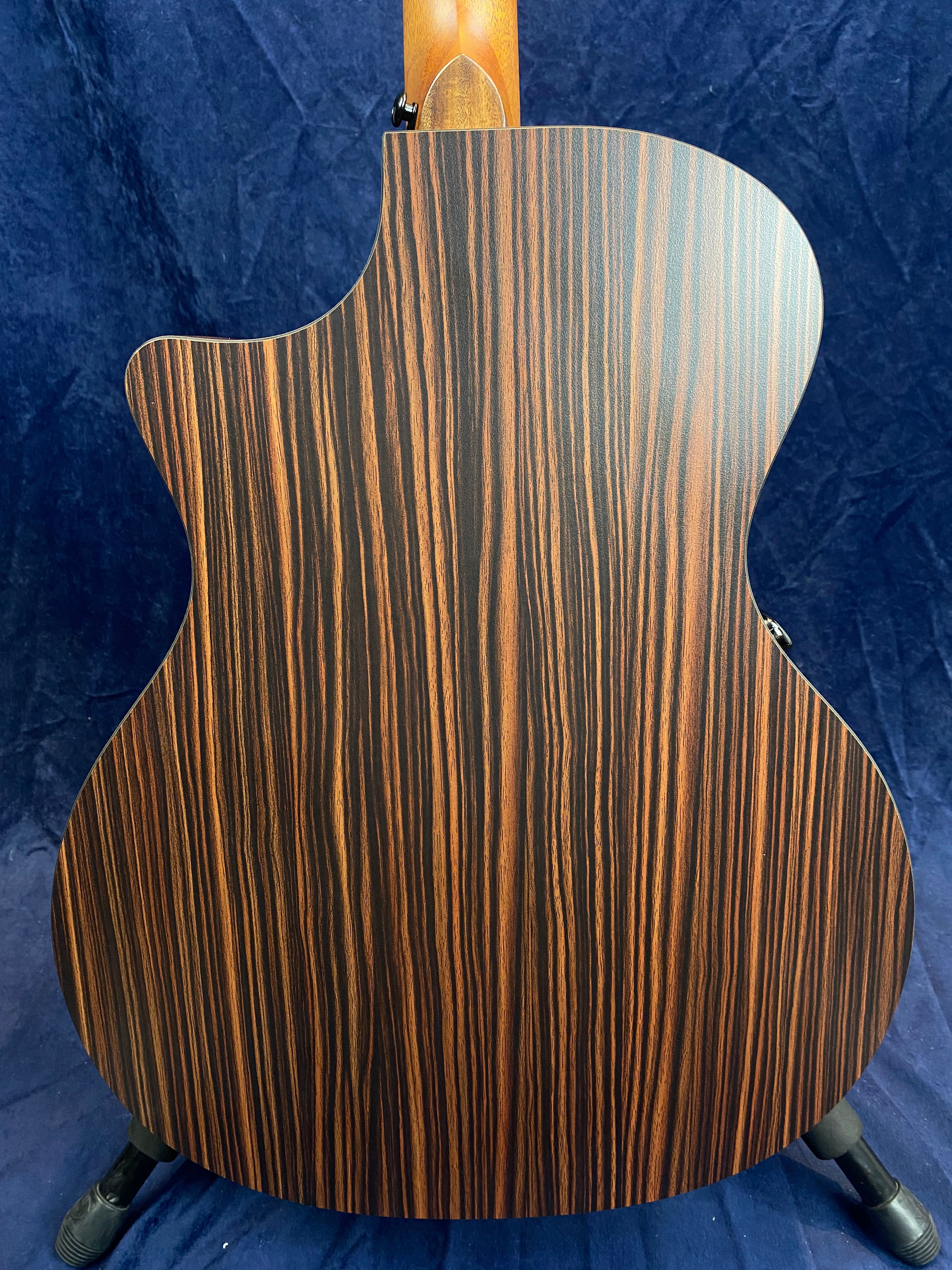 Acoustic guitar back with dark brown wood and striking vertical lighter brown stripes, matte finish, slightly curved cutaway design.
