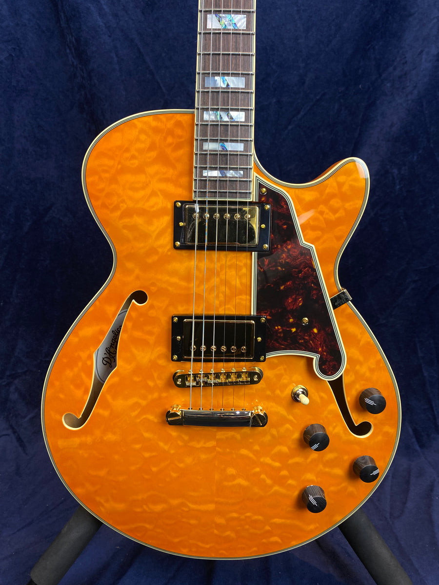 Semi-hollow electric guitar with quilted amber finish, two humbucker pickups, tortoiseshell pickguard, gold hardware, and four black control knobs.