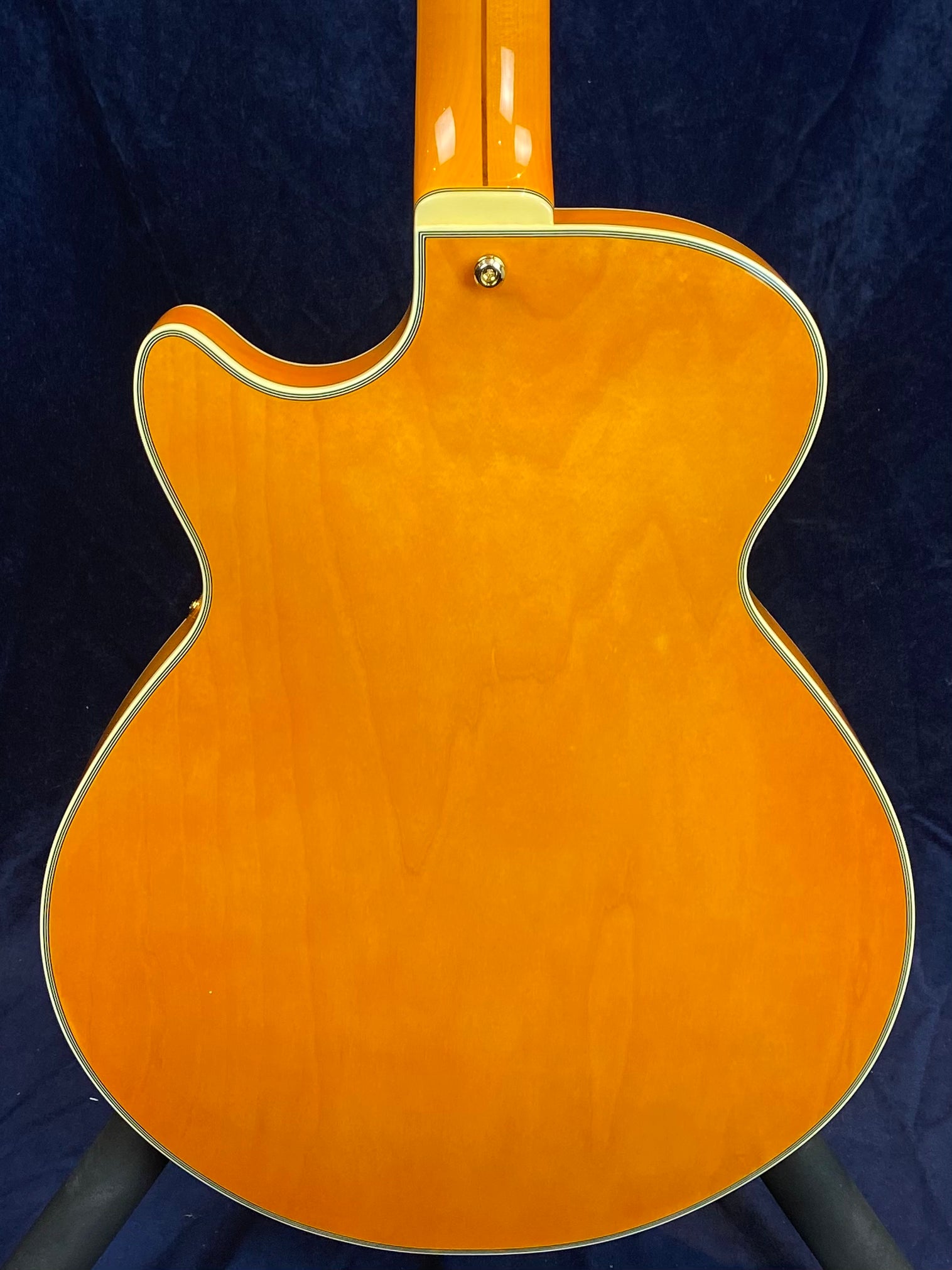 Orange electric guitar back with cream binding, a single cutaway design, and a gold strap button near the neck joint.