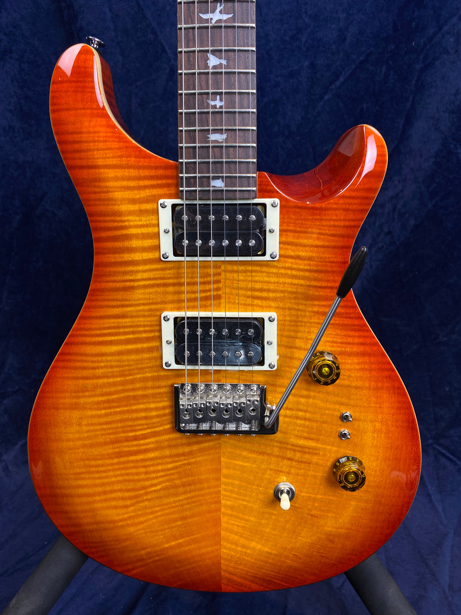 Sunburst electric guitar with two humbucker pickups, tremolo bridge, two amber knobs, toggle switch, and bird inlays on the fretboard.