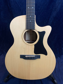 Light wood acoustic guitar with a black pickguard and cutaway design, six steel strings, dark bridge, and decorative soundhole rosette.