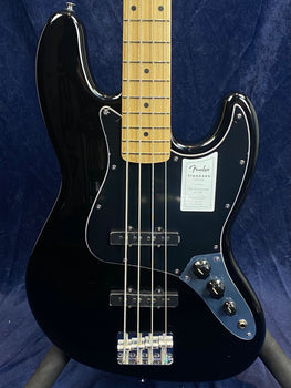Glossy black Fender electric bass with a maple neck, chrome bridge, three control knobs, and a black pickguard against a dark blue background.
