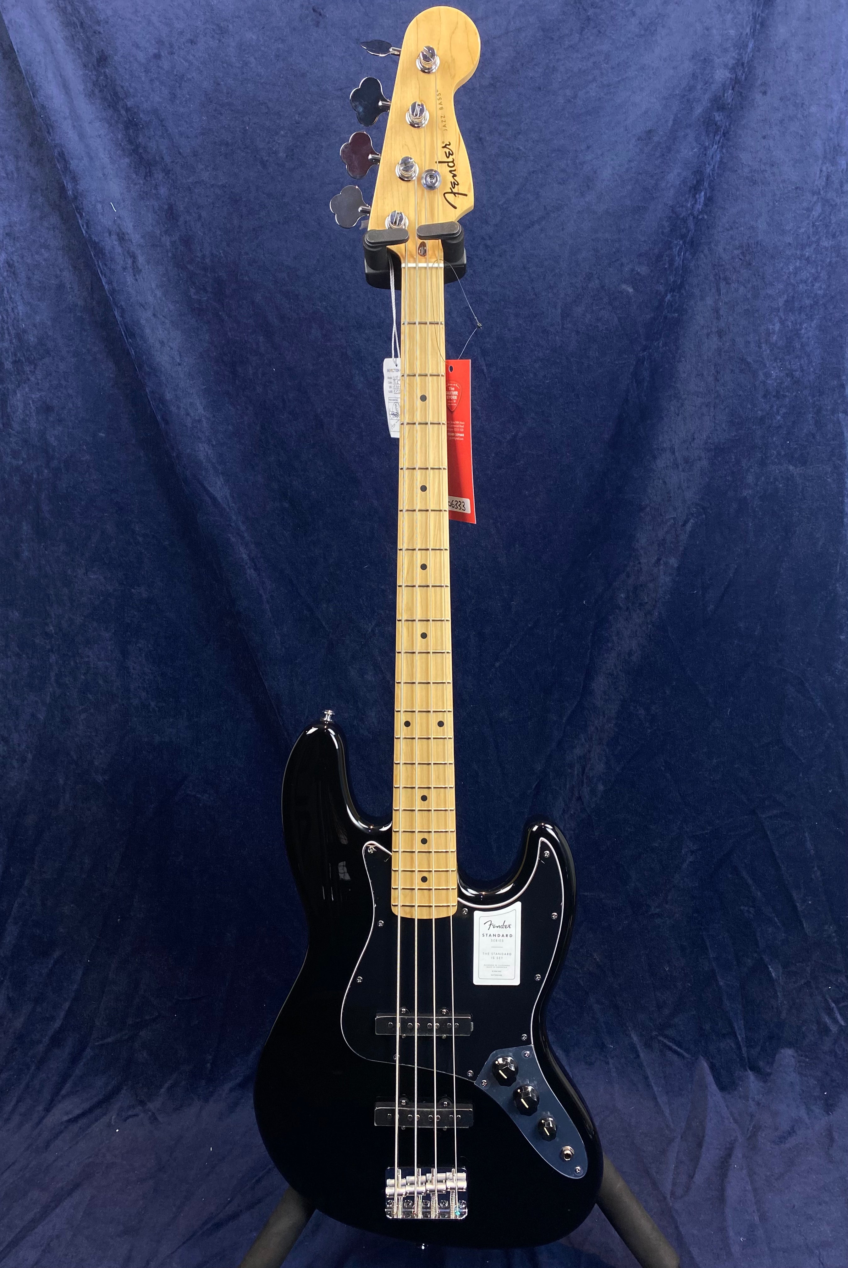 Black Fender electric bass with a maple neck, chrome hardware, four control knobs, and a single split-coil pickup, displayed against a dark blue background.