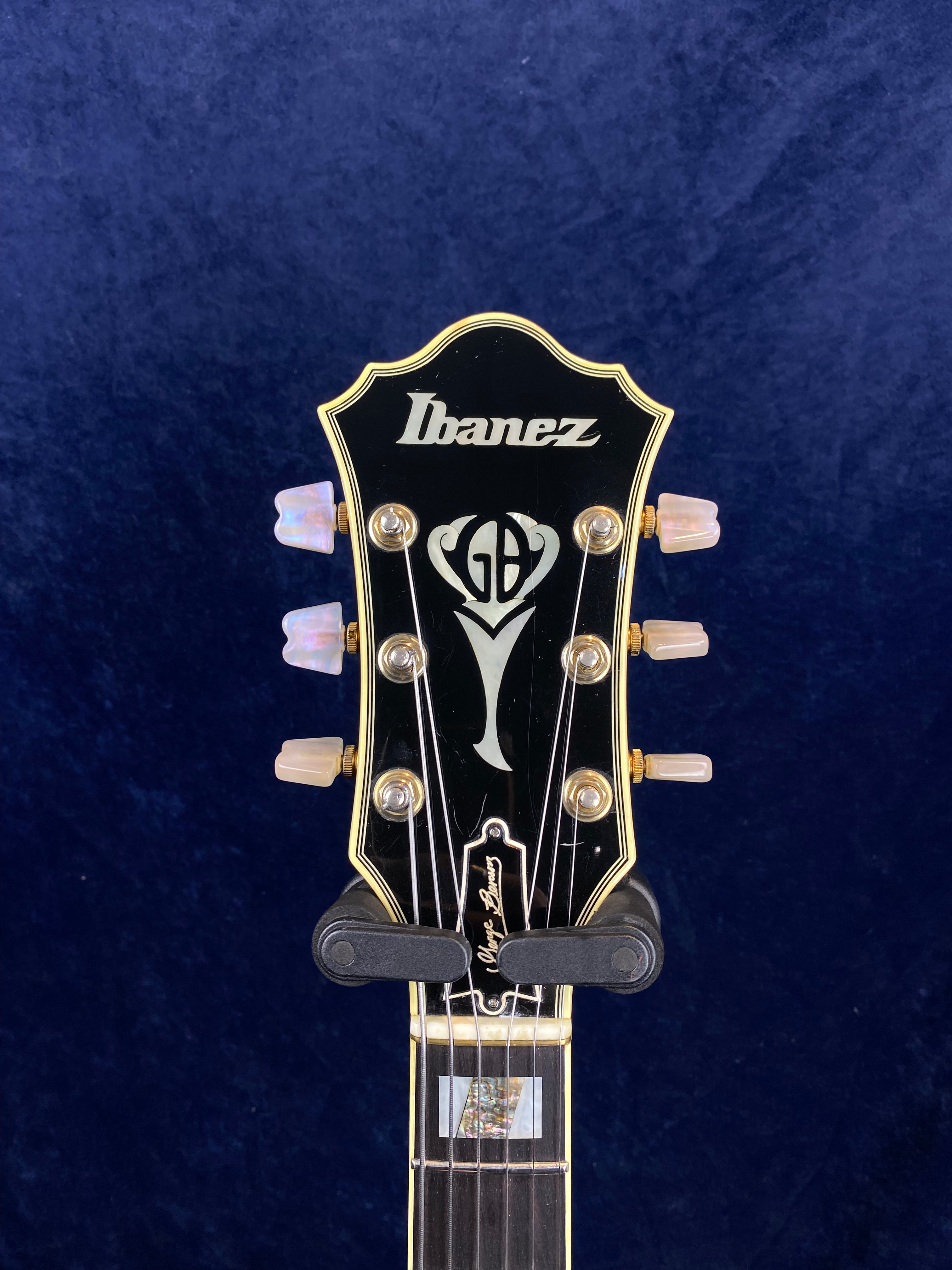 Ibanez electric guitar headstock with pearl tuner knobs, gold trim, GB inlay, and signature below the truss rod cover.