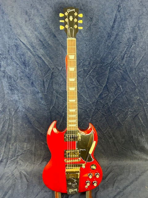 Bright red electric guitar with a double-cutaway body, chrome hardware, four control knobs, and a black pickguard against a dark blue background.
