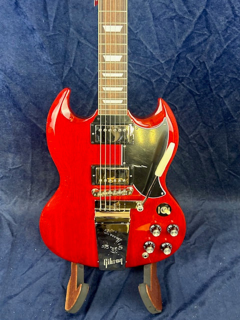 Bright red Gibson electric guitar with a double-cutaway body, chrome hardware, two pickups, four control knobs, and a whammy bar on a stand.