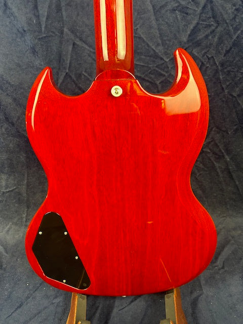 Glossy cherry red electric guitar shown from the back, with a double-cutaway body and a black plastic electronics cover near the bottom left.