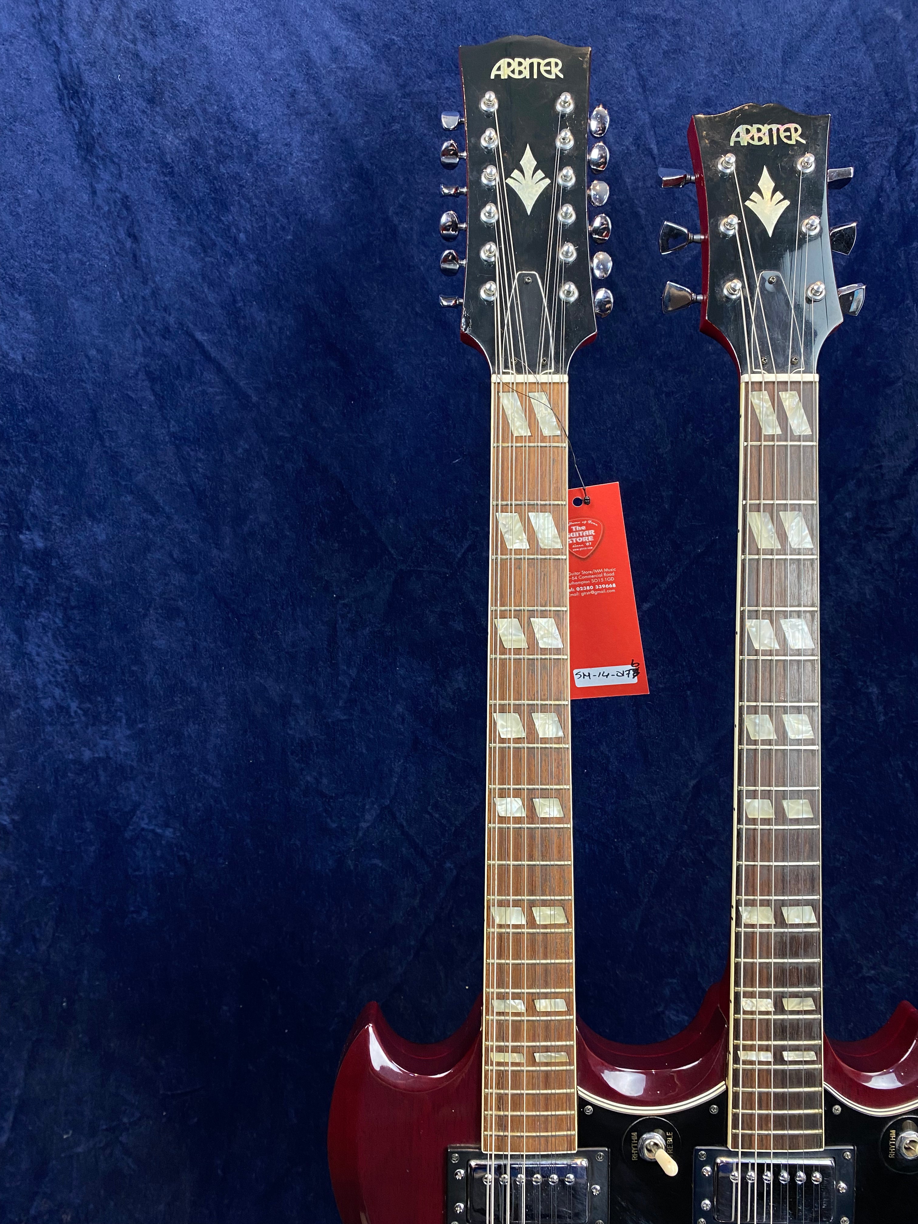 Two Arbiter double-neck electric guitars in cherry red finish, one with twelve strings and one with six strings, sharing a single body.