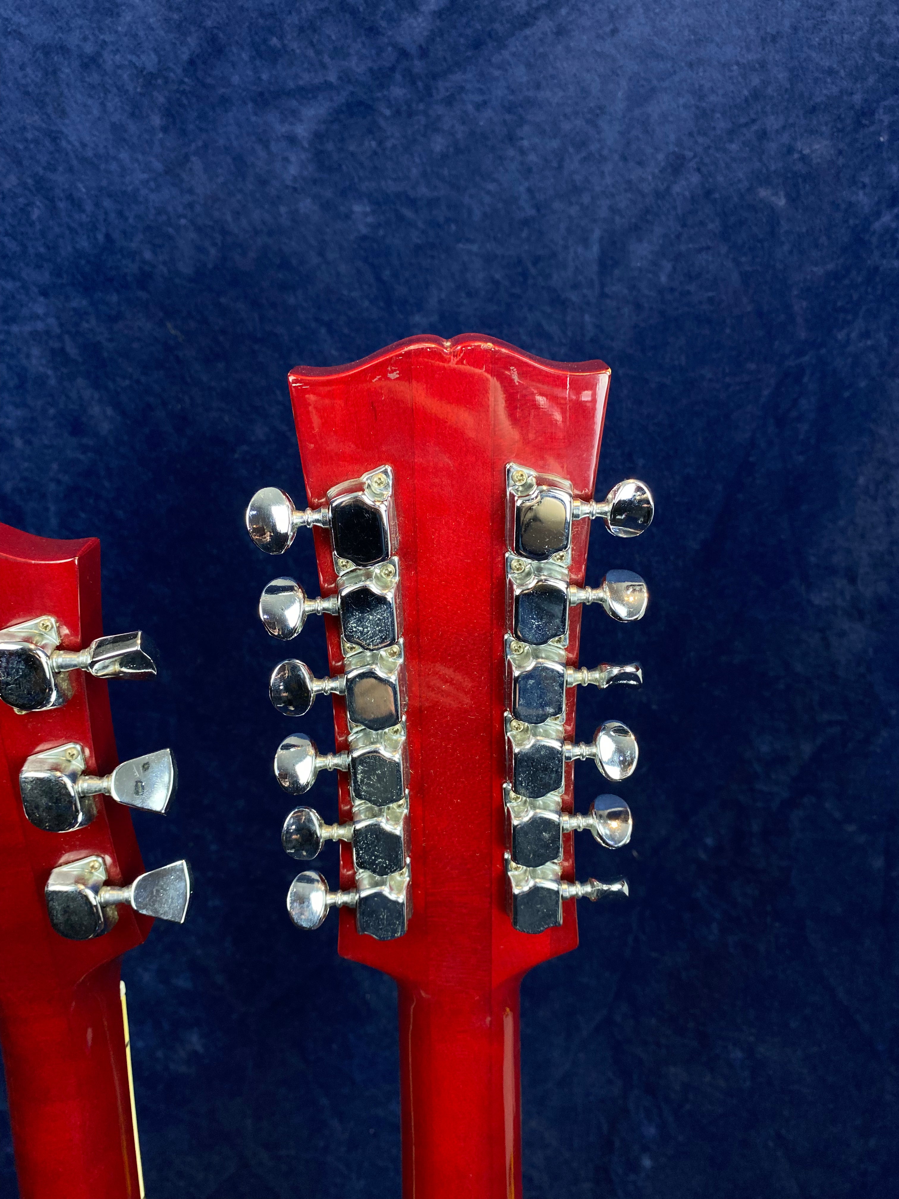 Two red electric guitars shown from the back, one with six tuning pegs and the other with twelve tuning pegs arranged in two rows.