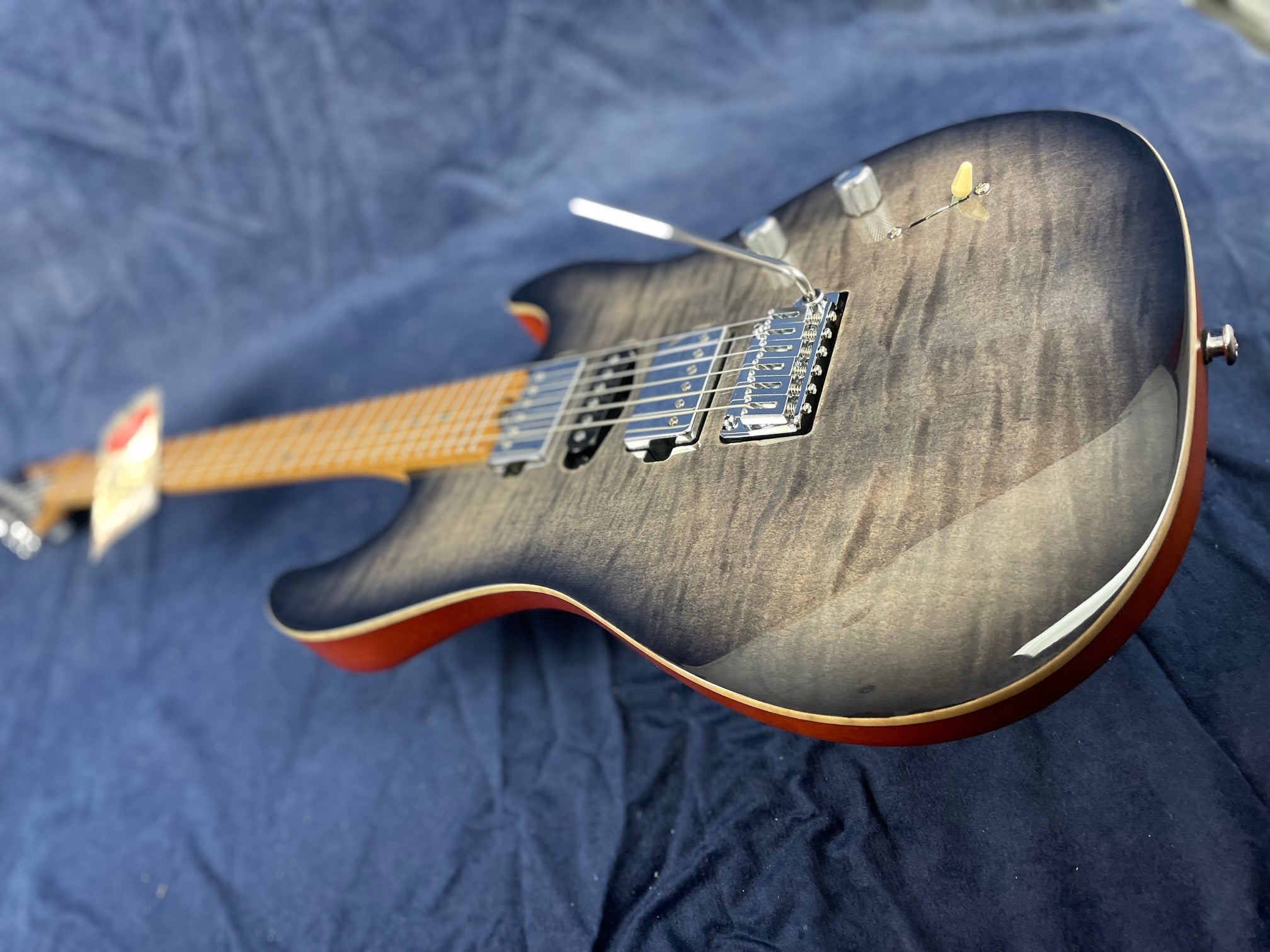 Electric guitar with a gray-black sunburst finish, visible wood grain, two humbucker pickups, a tremolo bar, and chrome control knobs.