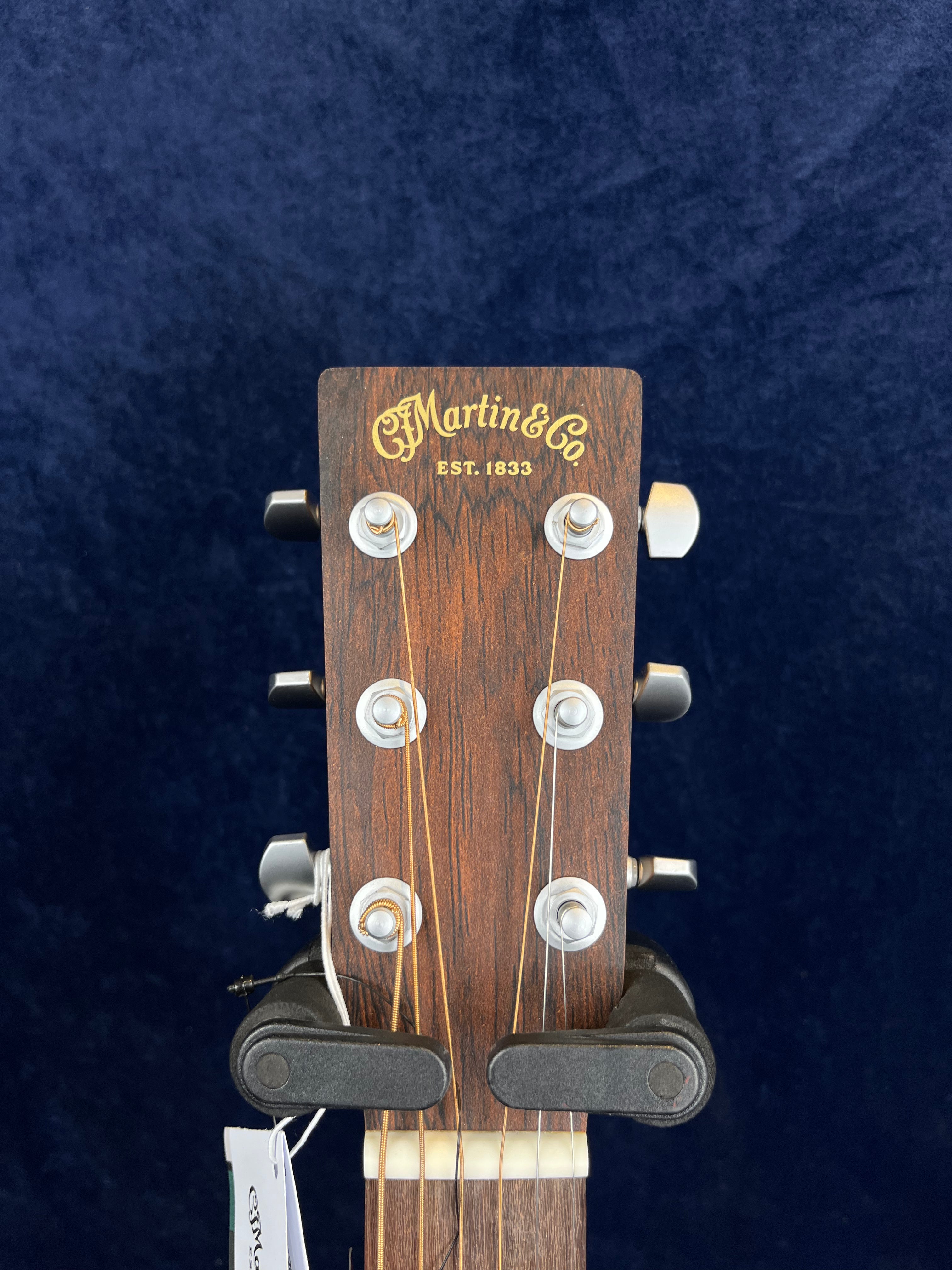 Close-up of a Martin & Co acoustic guitar headstock with six tuning pegs and gold logo on dark wood.
