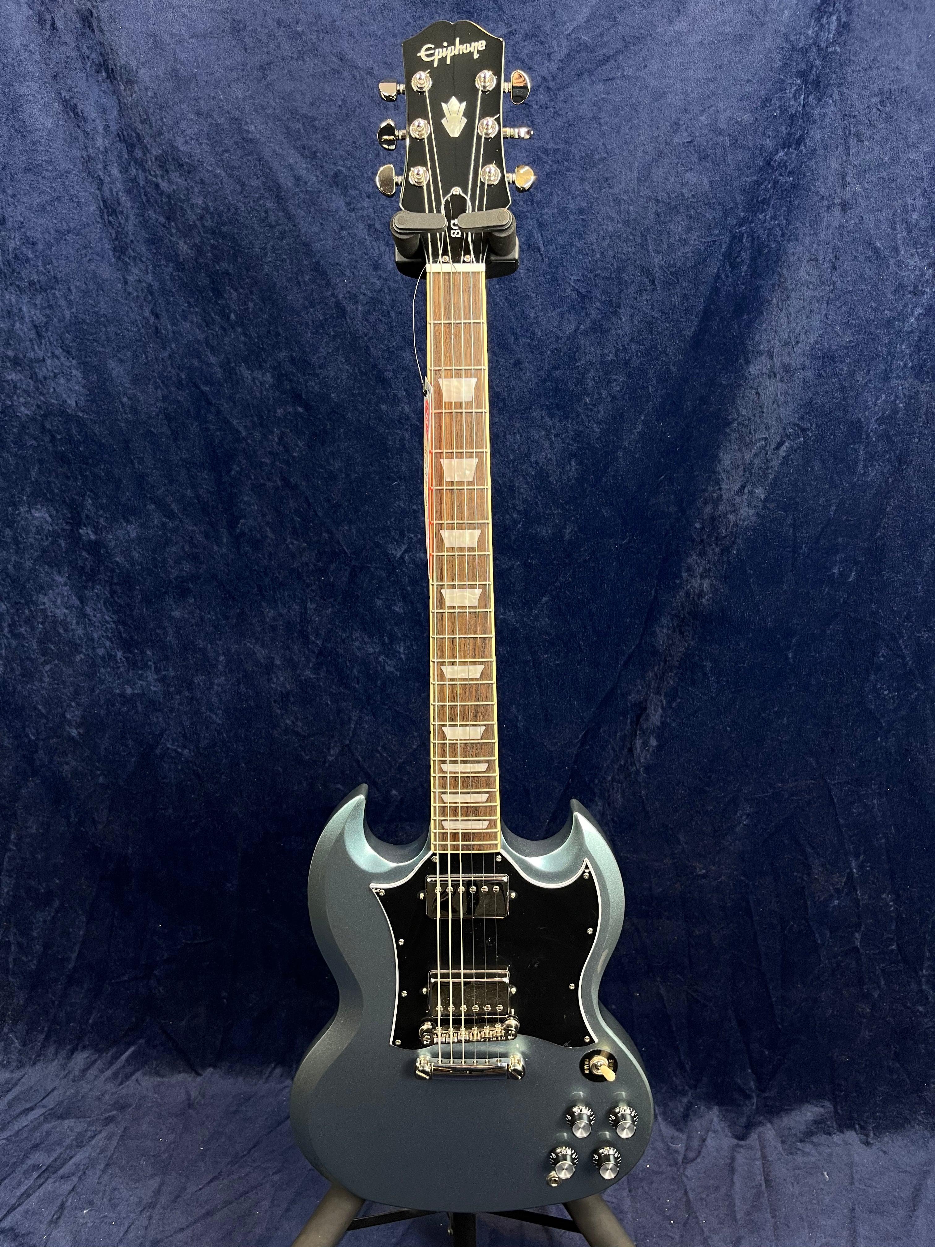 Epiphone electric guitar with a double-cutaway body in metallic blue, black pickguard, four control knobs, and chrome hardware against a dark background.