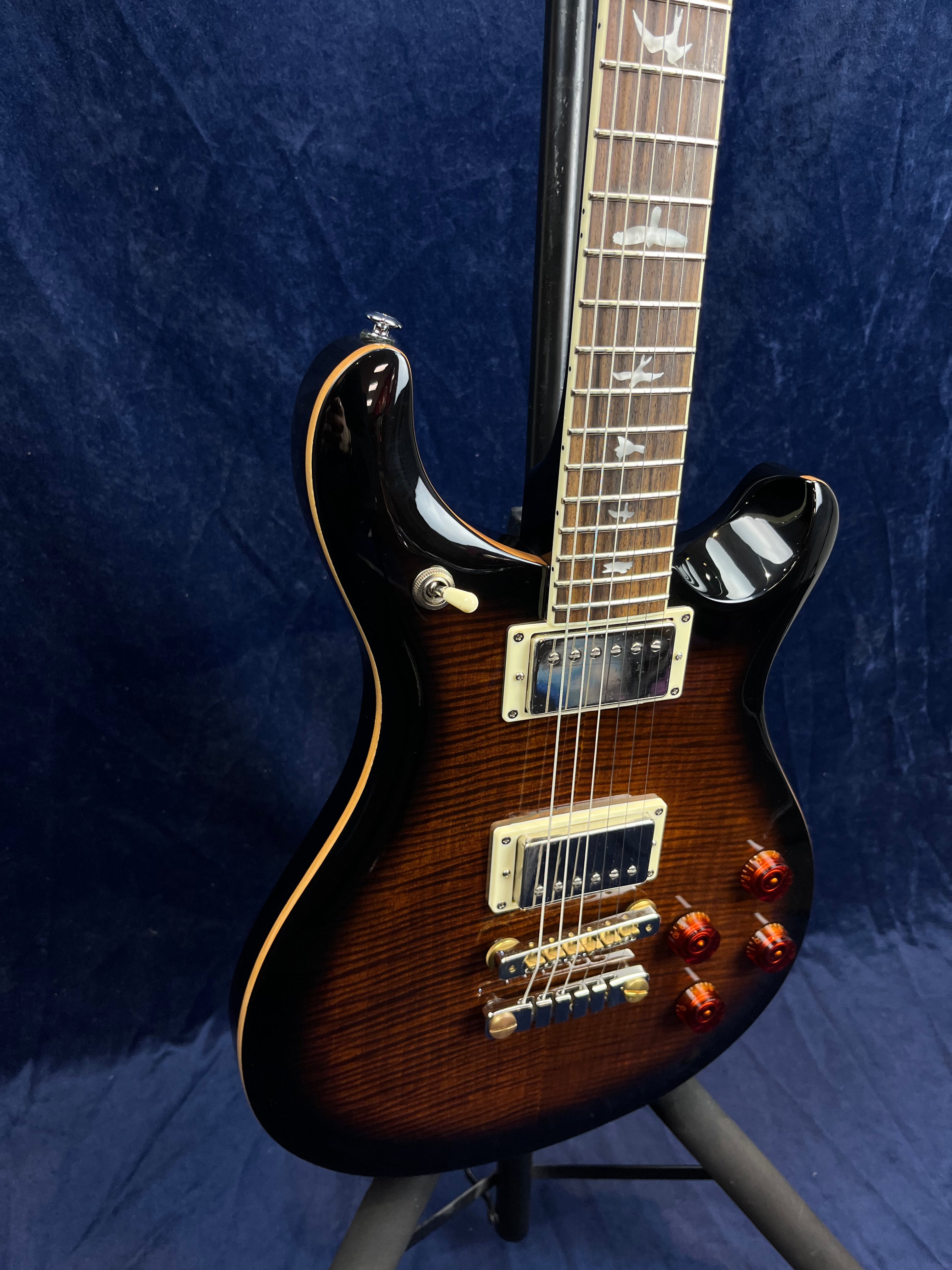 Electric guitar with a dark sunburst finish, two humbucker pickups, gold hardware, and bird inlays on the rosewood fretboard.