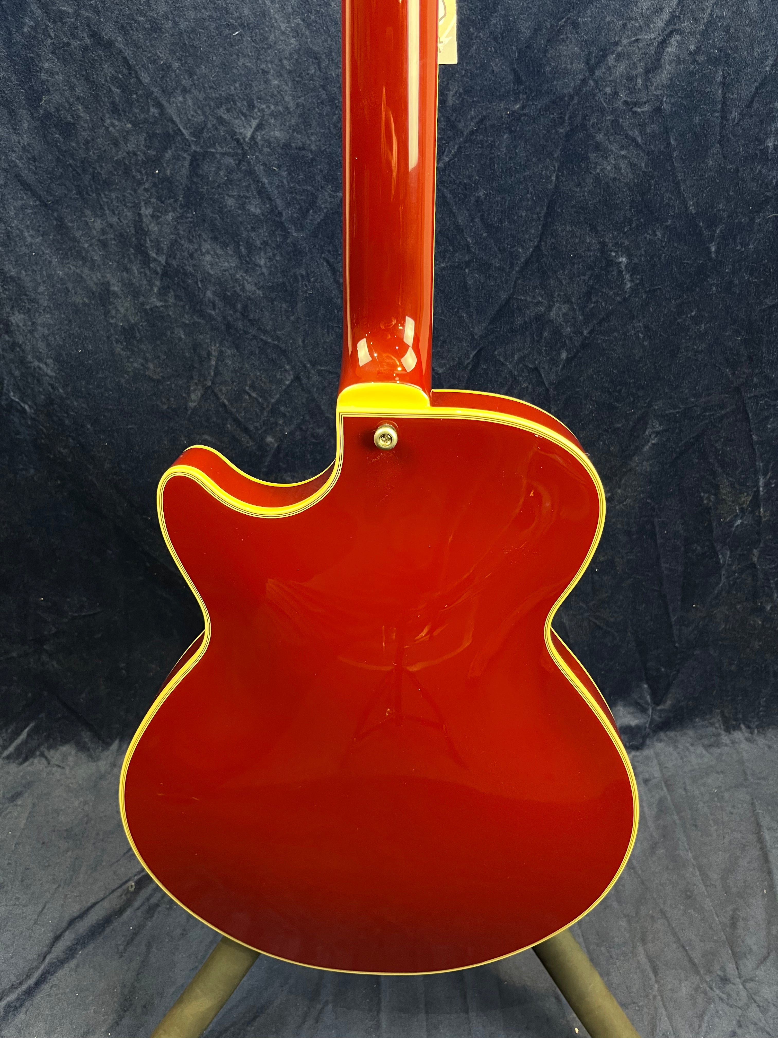 Red electric guitar viewed from the back, featuring a glossy finish and cream-colored binding along the edges.