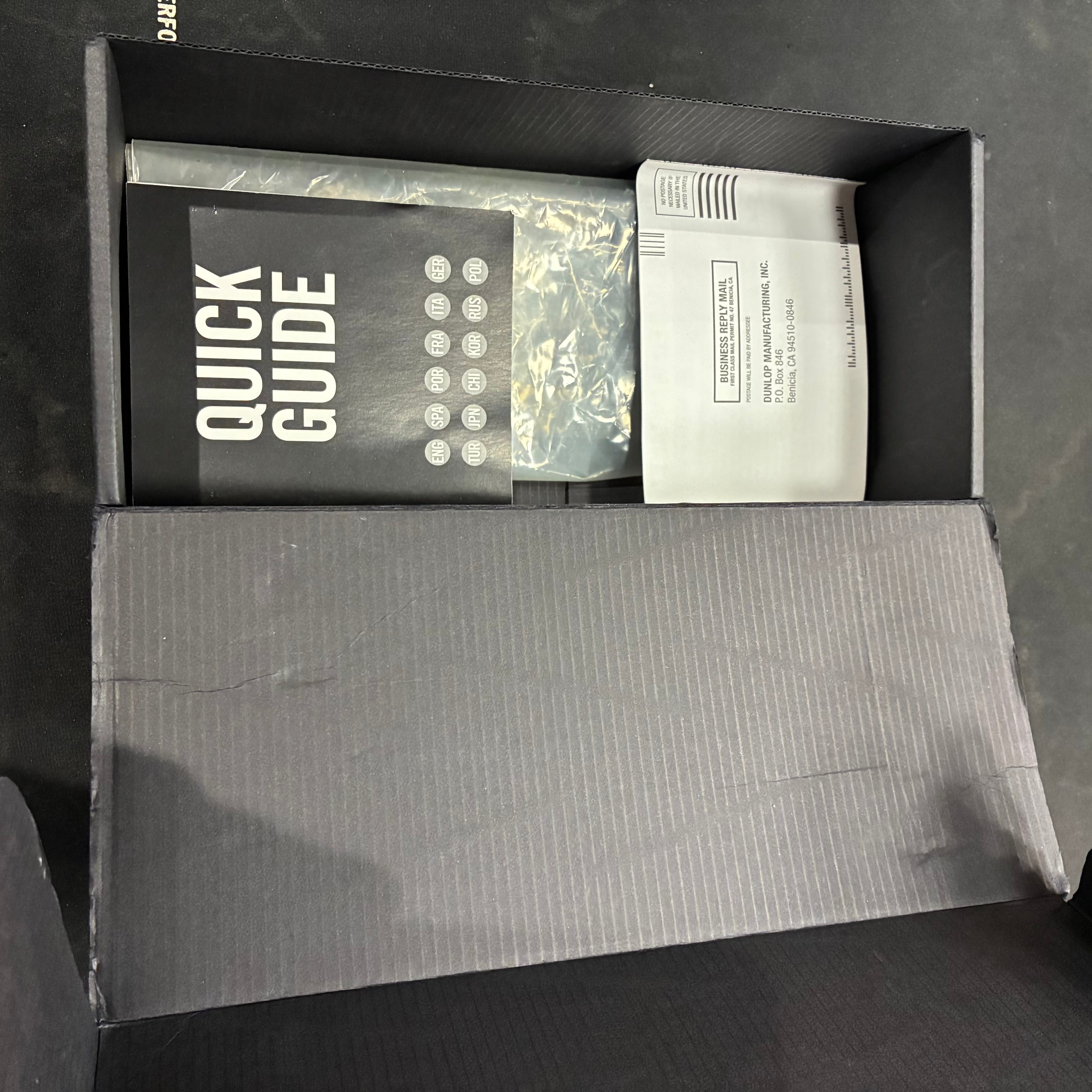 Cardboard FX pedal box opened to reveal a quick guide booklet and a folded warranty or registration card inside. Pedal itself not visible.