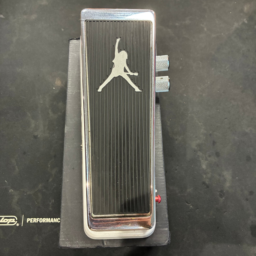 Black and chrome FX pedal with a silhouette of a person playing guitar engraved on top, two side knobs, and a red LED indicator.