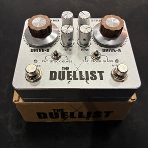 Guitar FX pedal named The Duellist, featuring two large brown knobs, four silver knobs, two metal switches, and two footswitches on a silver casing.