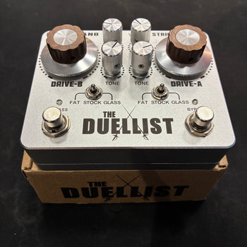 Guitar FX pedal named The Duellist, featuring two large brown knobs, four silver knobs, two metal switches, and two footswitches on a silver casing.