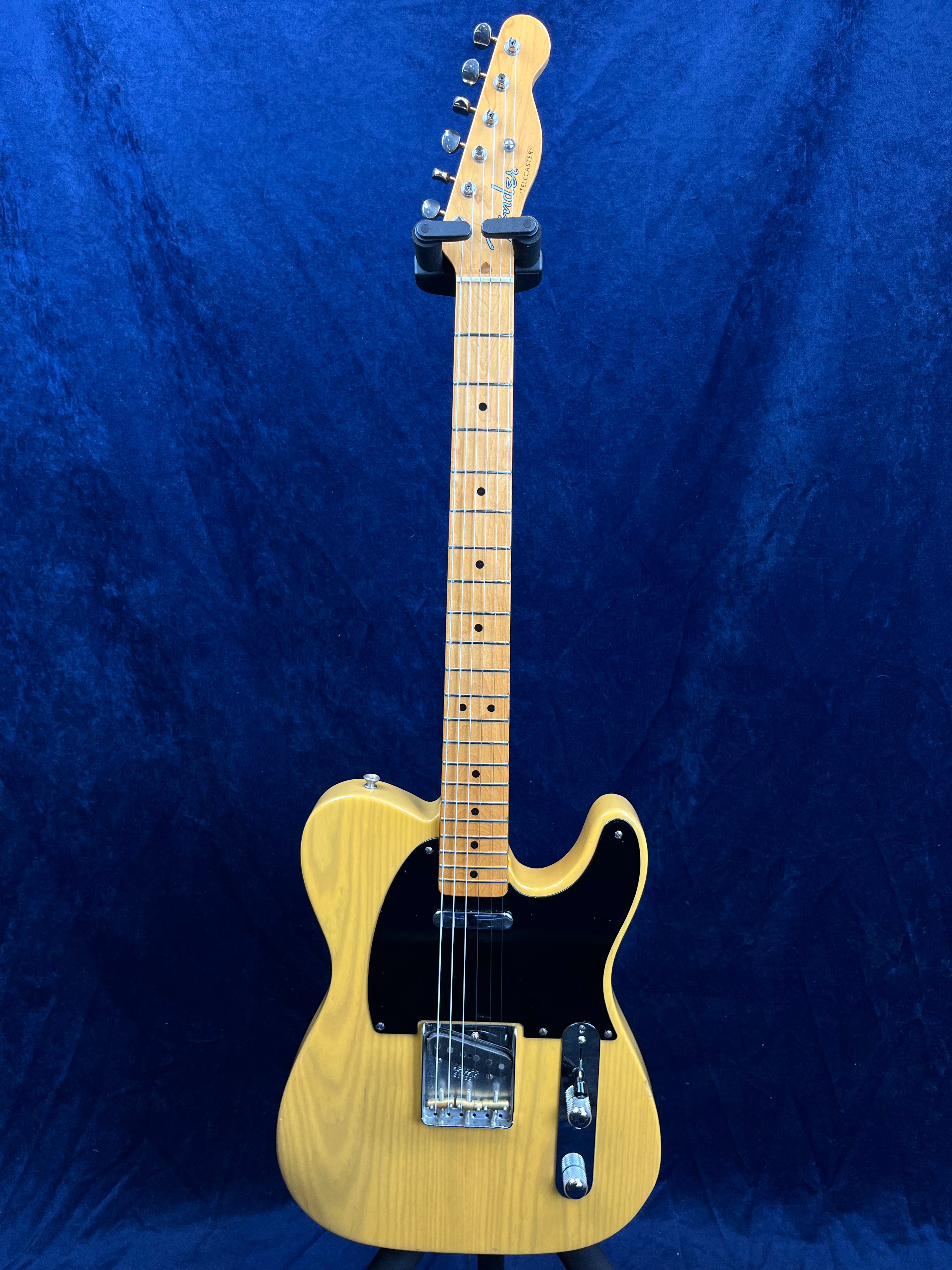 Butterscotch yellow electric guitar with black pickguard, light-colored neck and fretboard, chrome hardware, and single cutaway body.