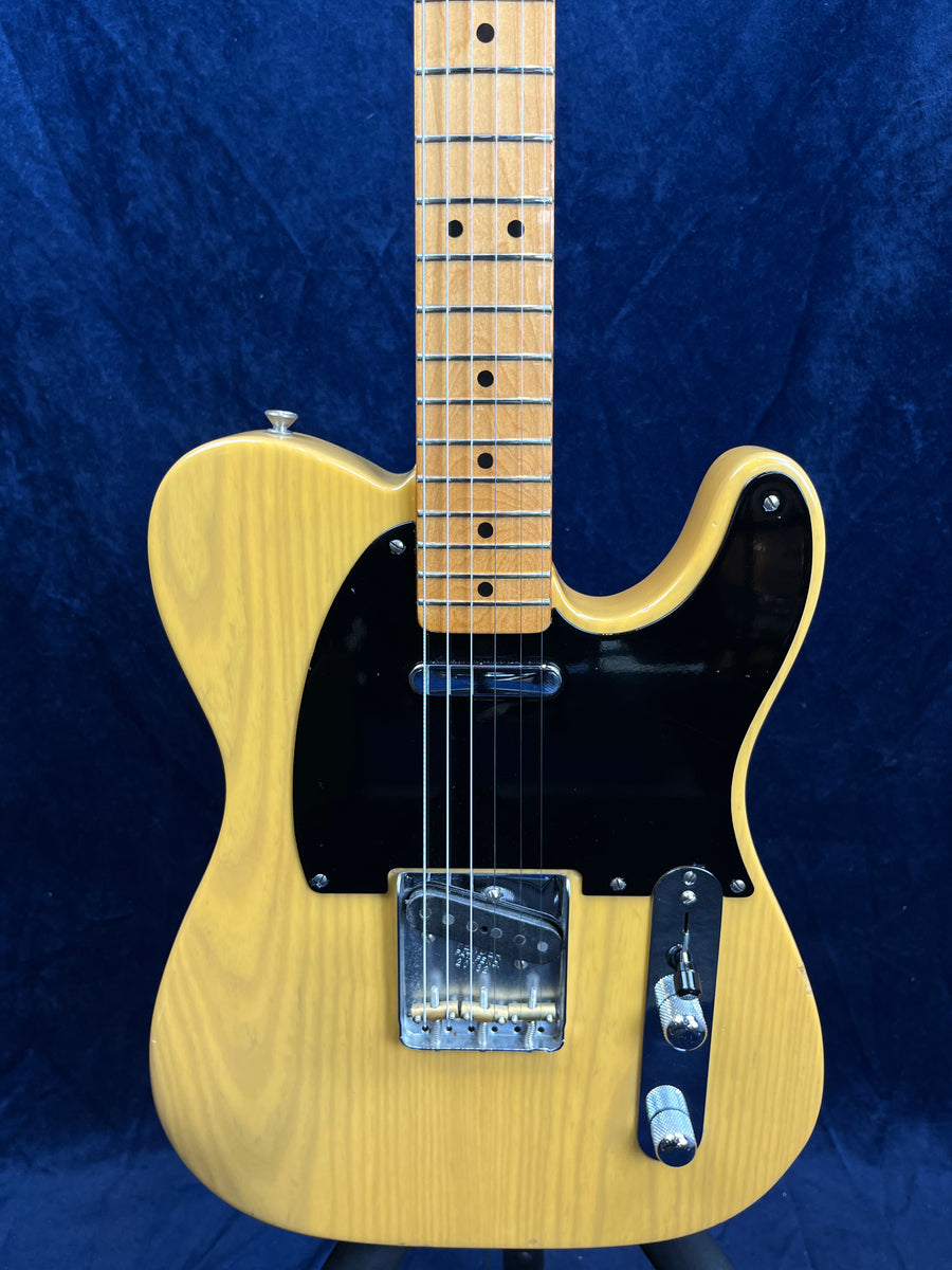 Yellow electric guitar with a black pickguard, two chrome control knobs, and a light wood neck, shown against a dark blue background.