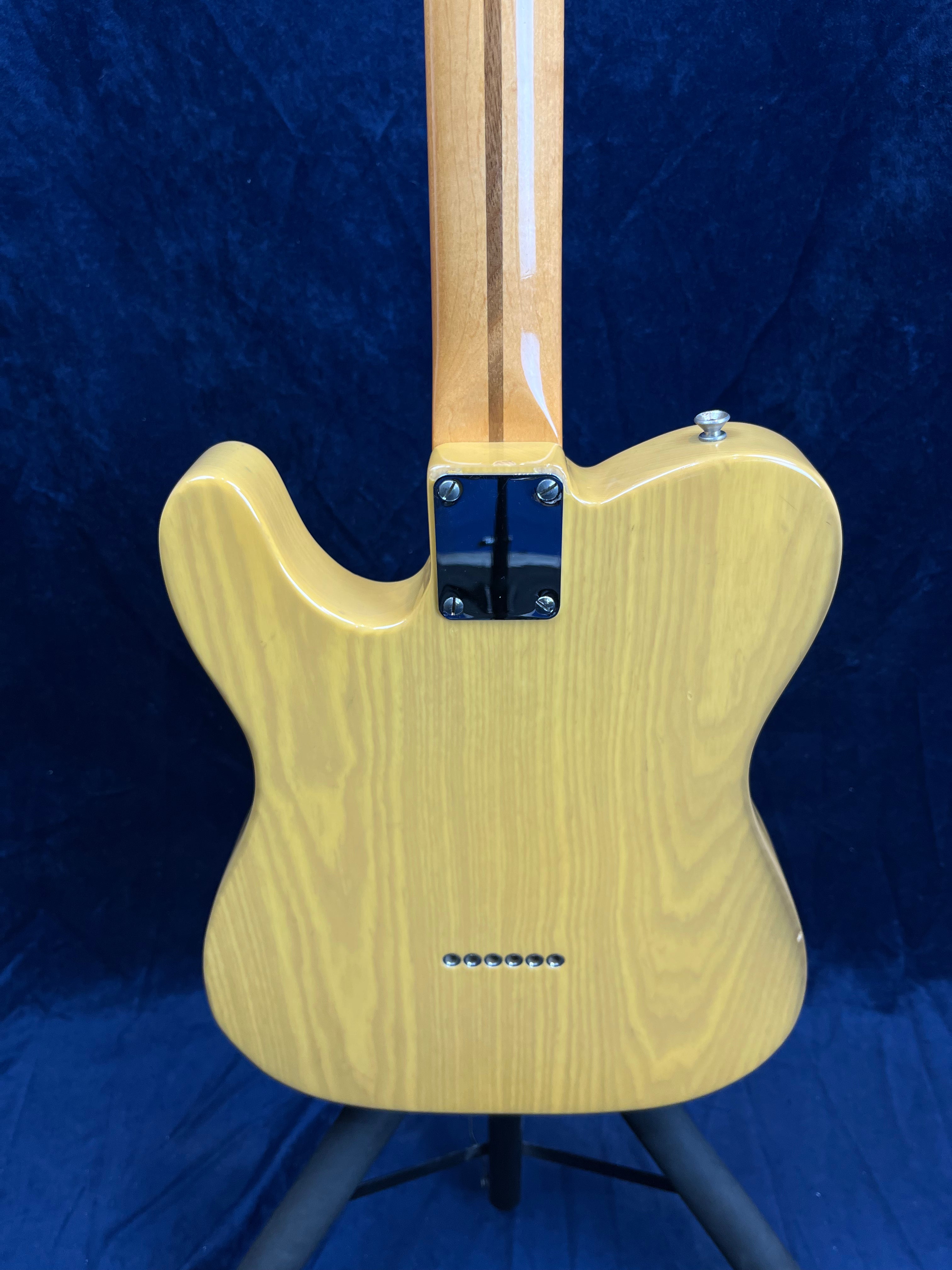 Light wood electric guitar shown from the back, with visible neck bolts, string-through body ferrules, and natural wood grain finish.