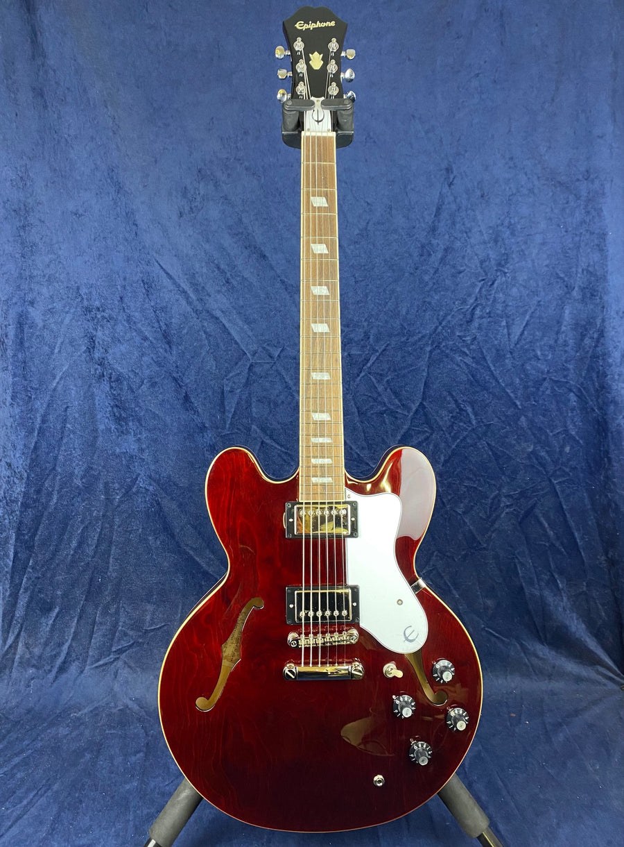 Cherry red semi-hollow body electric guitar with double cutaways, two humbucker pickups, a white pickguard, and four black control knobs.