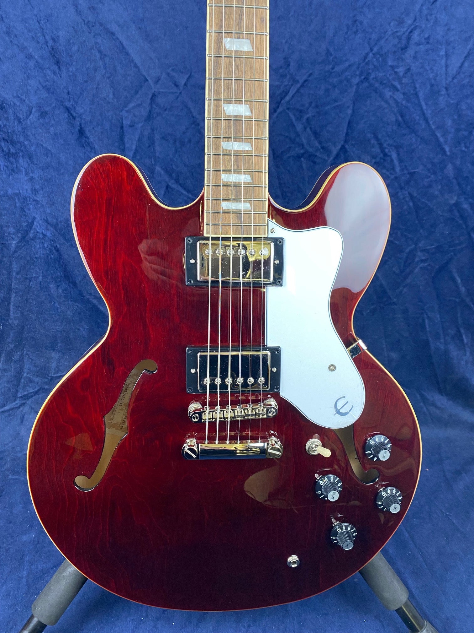 Cherry red semi-hollow electric guitar with two humbucker pickups, white pickguard, four black control knobs, and f-hole cutouts on both sides.