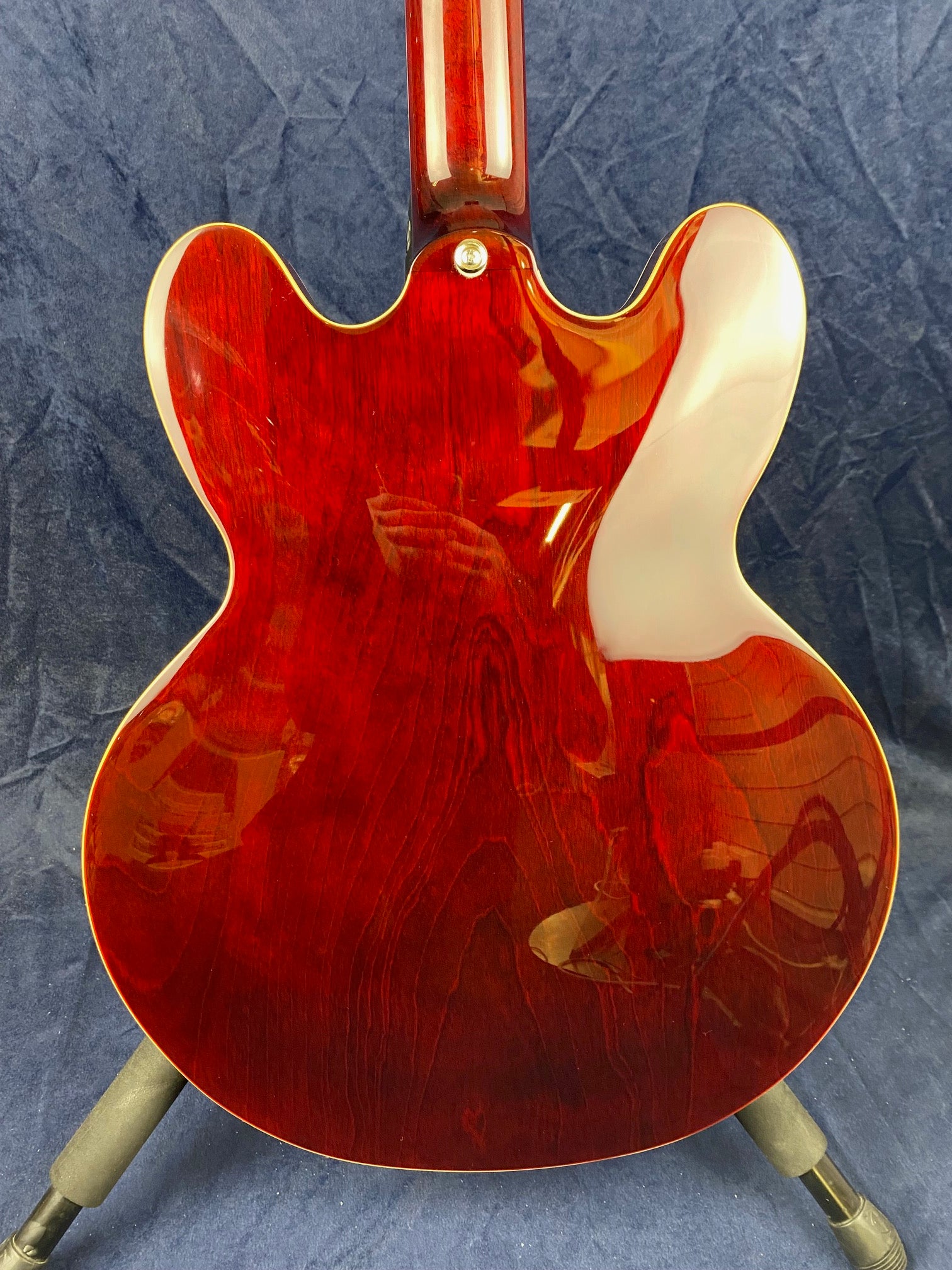 Glossy cherry red electric guitar body with visible wood grain, double cutaway shape, and yellowed binding around the edges, shown from the back.