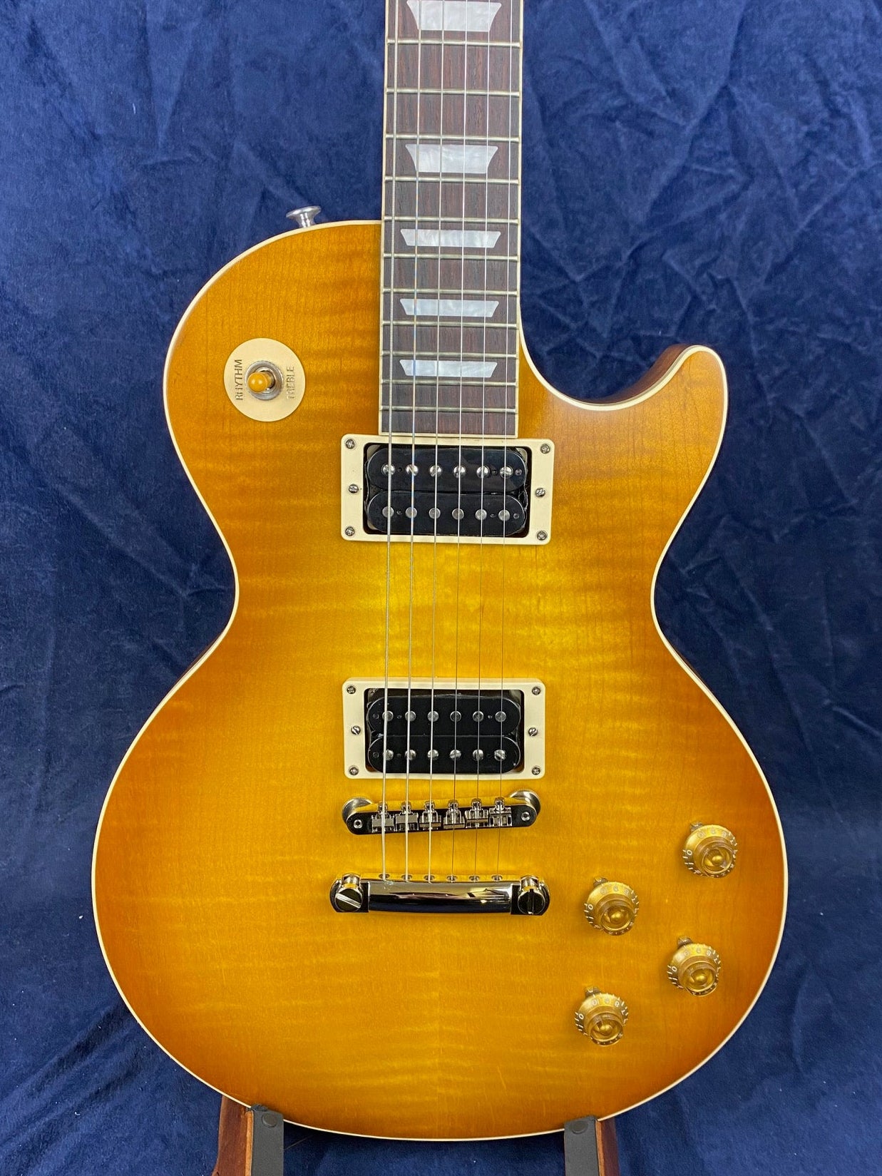 Sunburst finish electric guitar with a single cutaway, two humbucker pickups, four gold control knobs, and a three-way toggle switch.