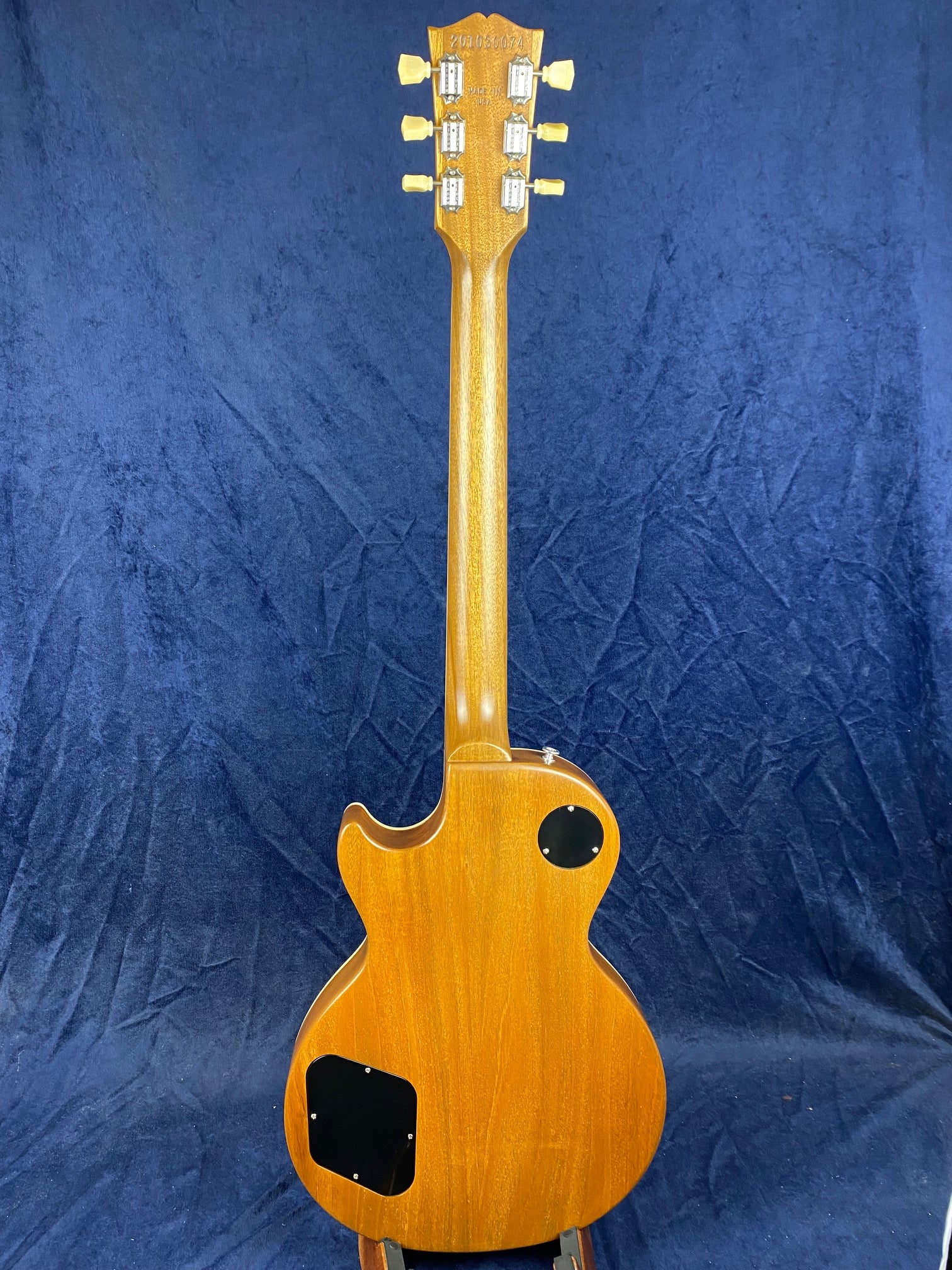 Natural wood finish electric guitar shown from the back, revealing tuning pegs, smooth neck, and two black access panels on the body.